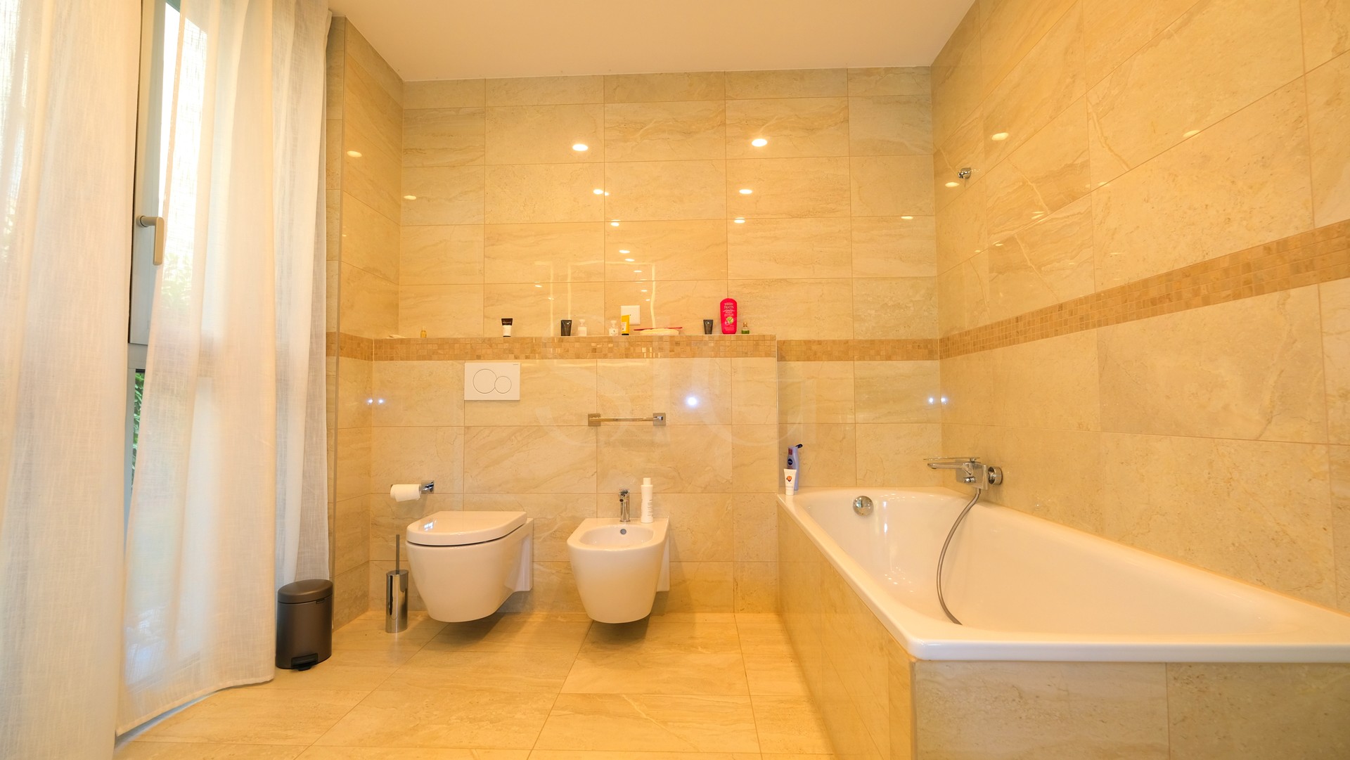 Luxuriöses Badezimmer mit Badewanne und beige gefliesten Wänden