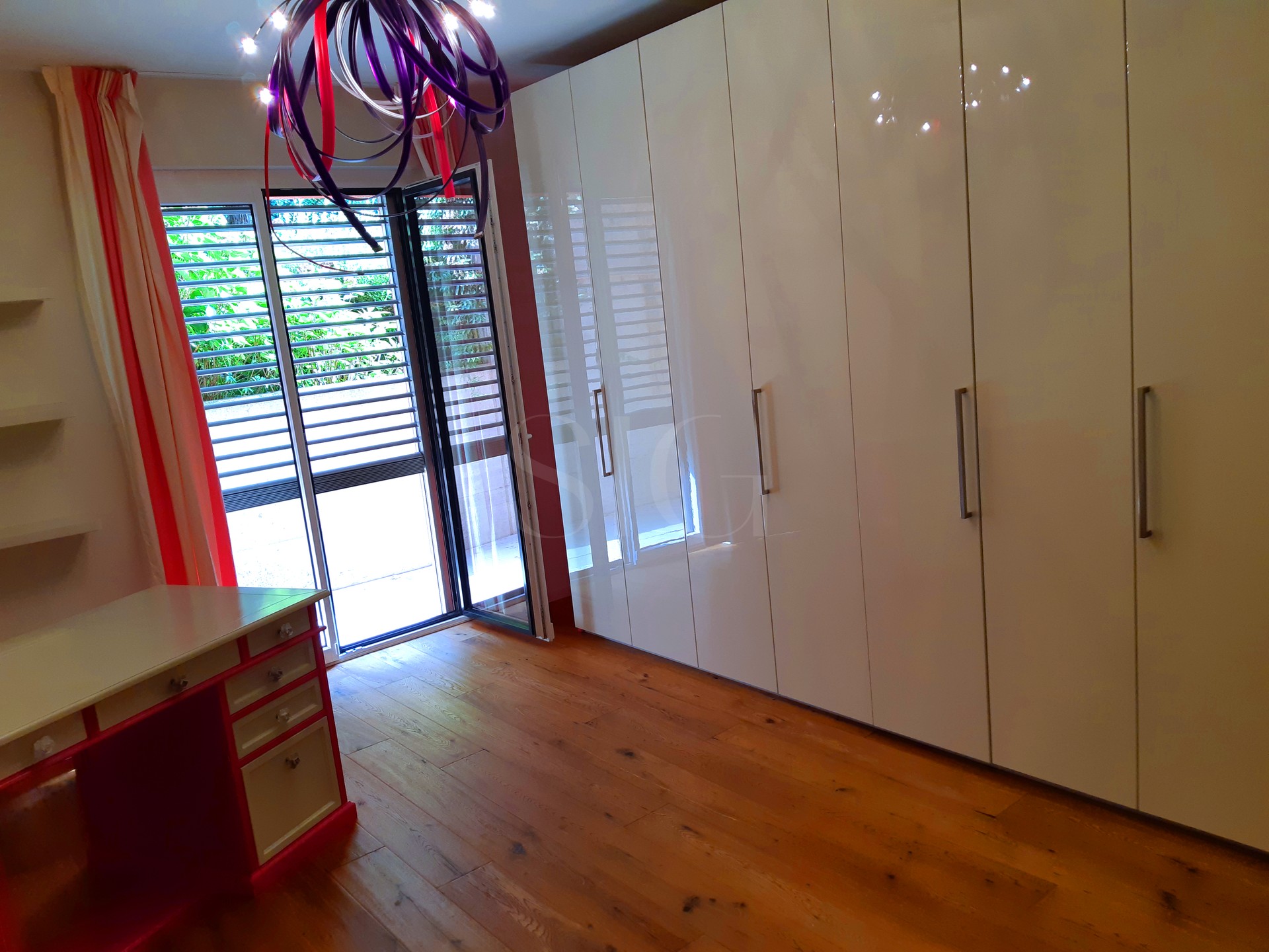 Schlafzimmer mit Einbauschränken und Balkonzugang