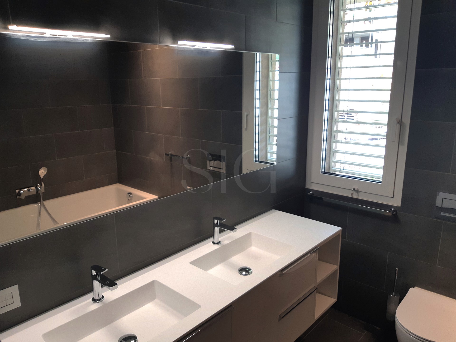 Modernes Badezimmer mit dunkler Fliesenoptik und Doppelwaschtisch