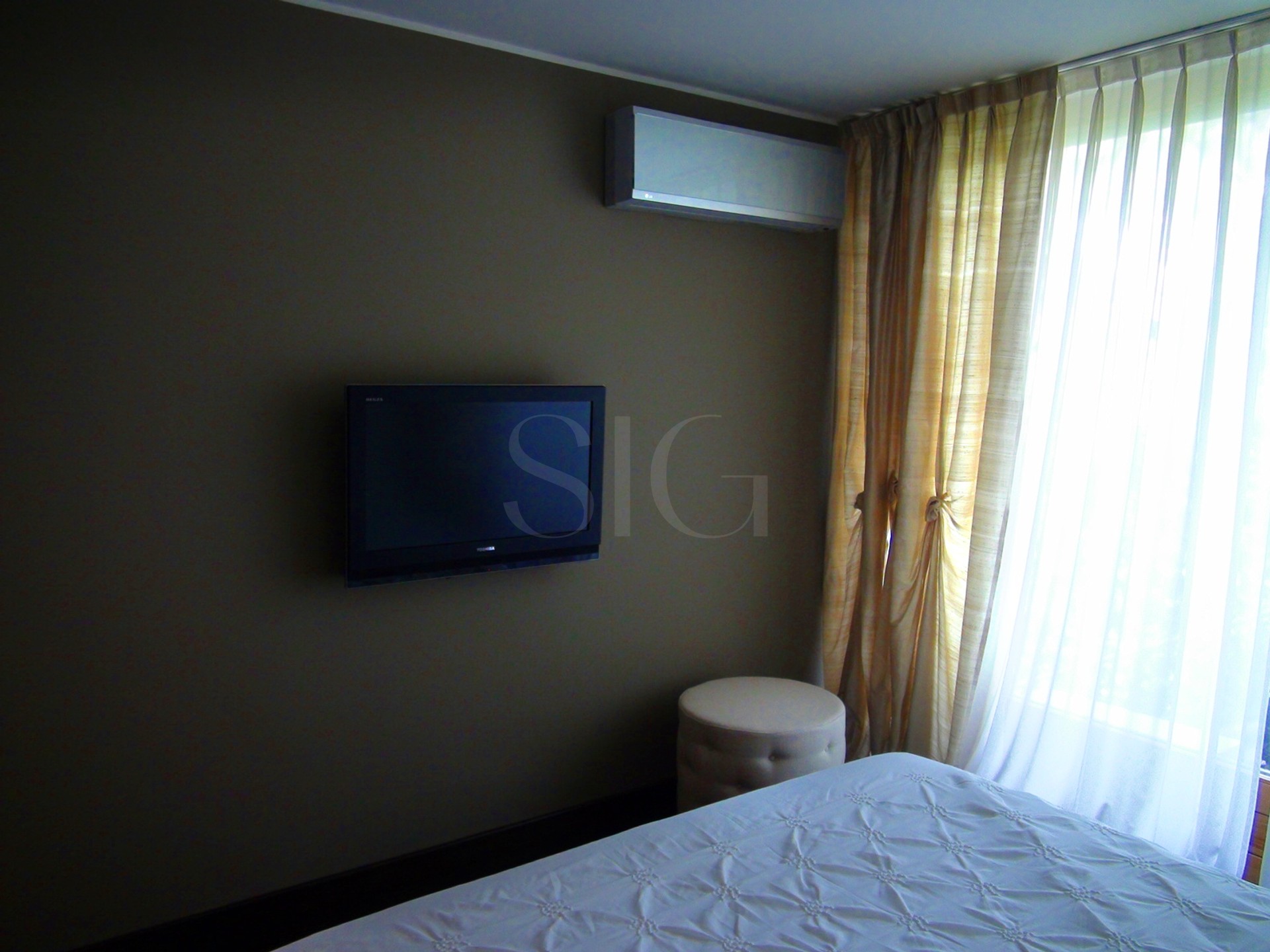 Schlafzimmer mit Wand-TV und Fenster