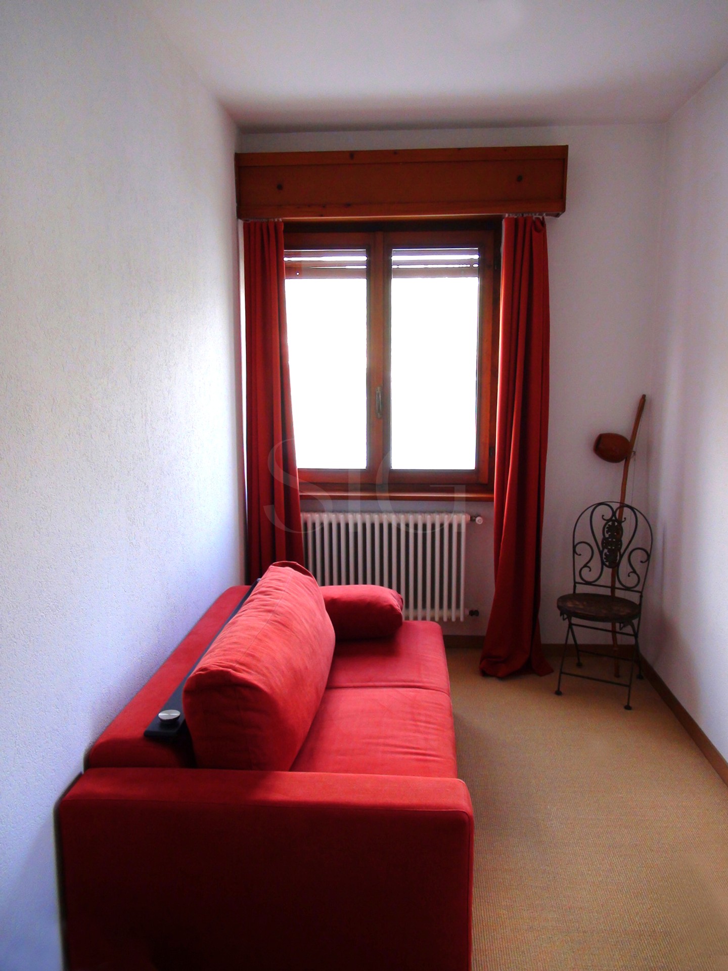 Kleines Wohnzimmer mit rotem Sofa am Fenster