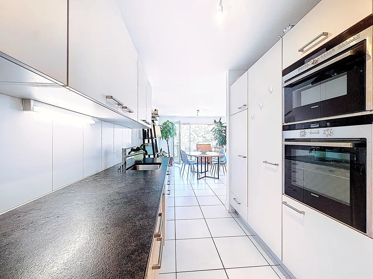 Moderne schmale Küche mit Essbereich im Hintergrund