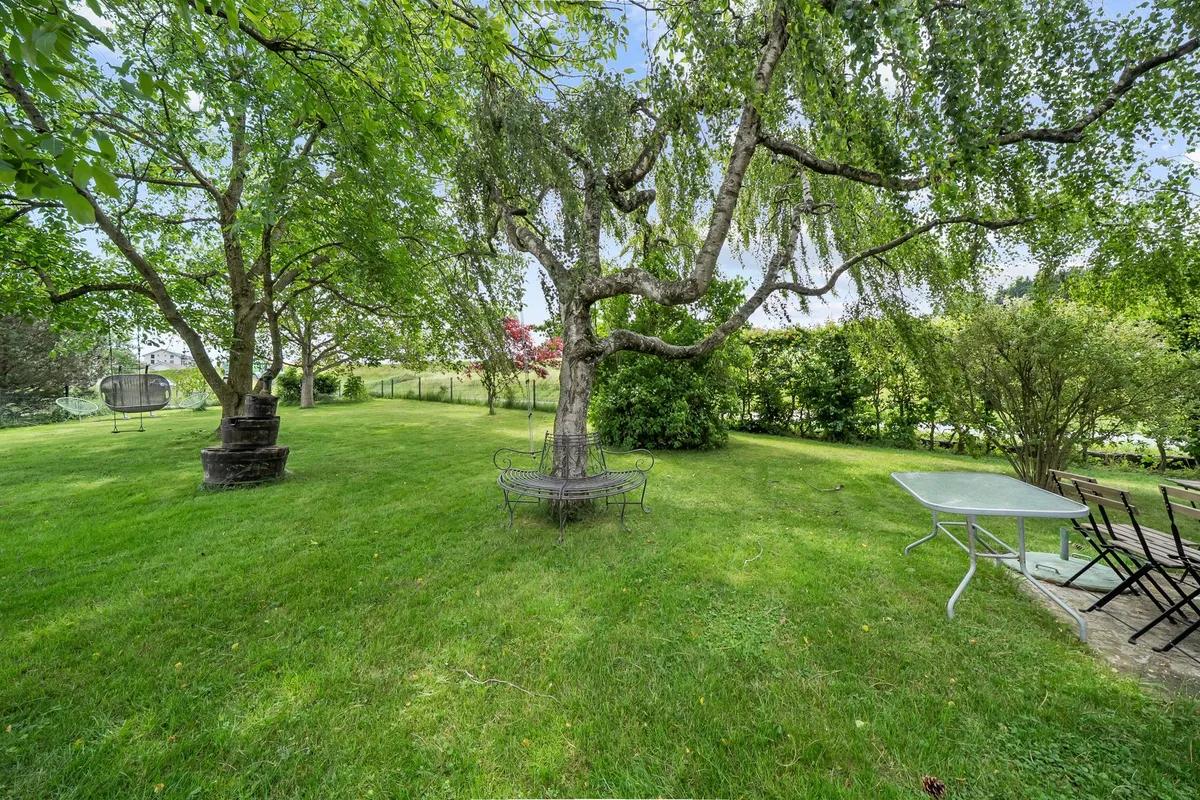 Großer grüner Garten mit Sitzplätzen unter Bäumen