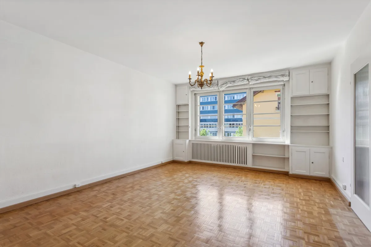 Heller leerer Wohnraum mit Parkett und Fensterwand
