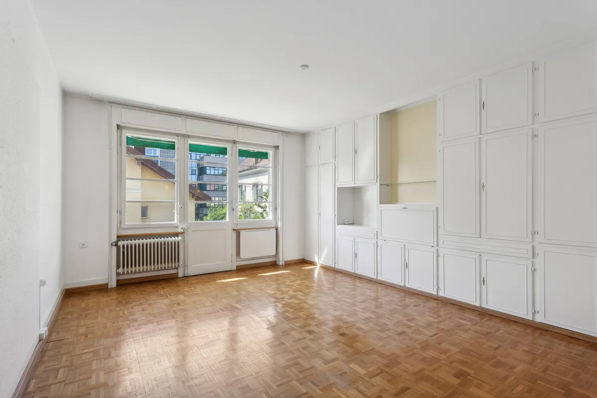 Heller, leerer Wohnraum mit Einbauschränken und Balkon-/Fenstertür