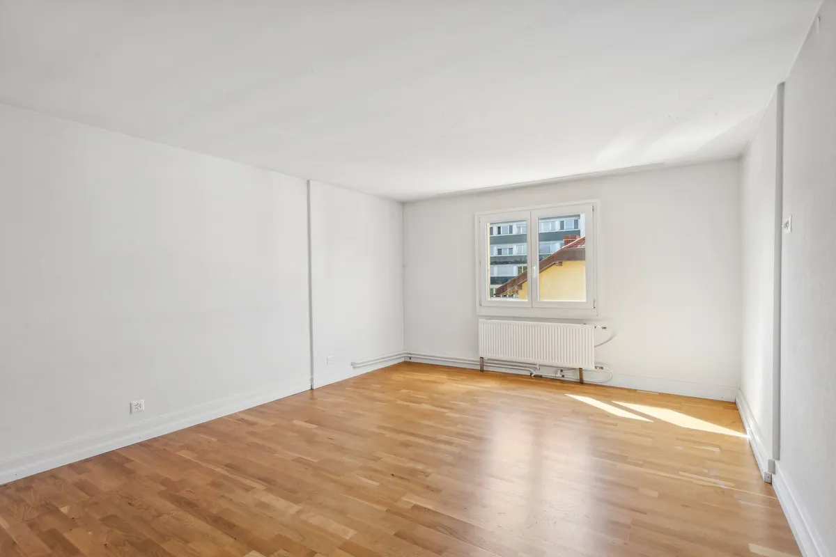 Leerer, heller Wohnraum mit Parkett und Fenster