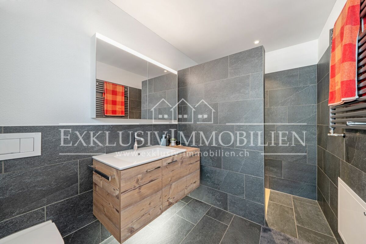 Modernes Badezimmer mit Holzwaschtisch und dunkler Natursteinoptik