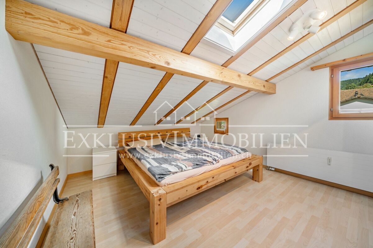 Dachgeschoss-Schlafzimmer mit sichtbaren Holzbalken