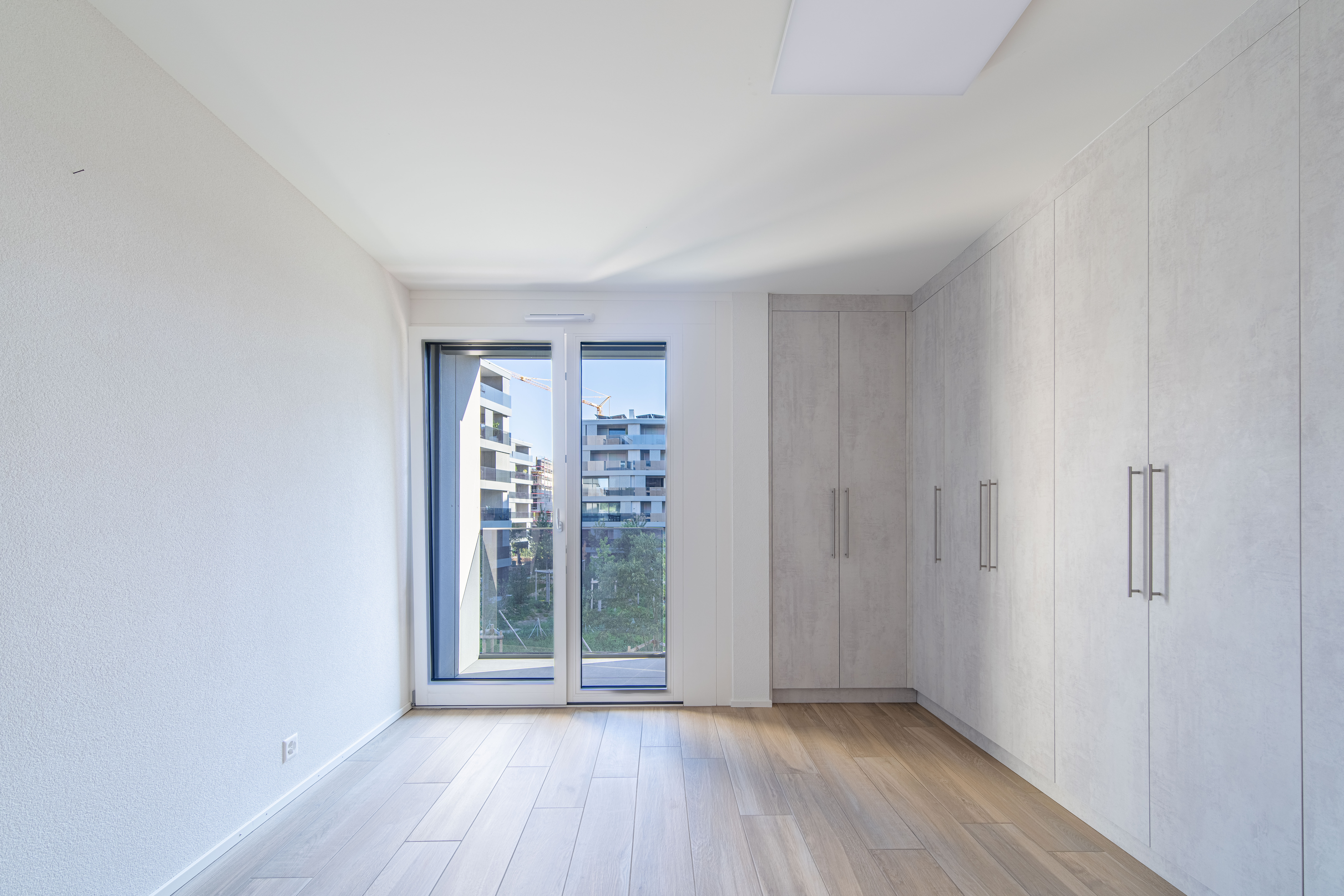 Helles, modernes Schlafzimmer mit Einbauschrank und Balkonblick