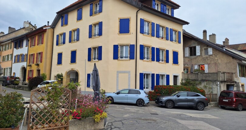 Straßenansicht eines Wohngebäudes mit blauen Fensterläden