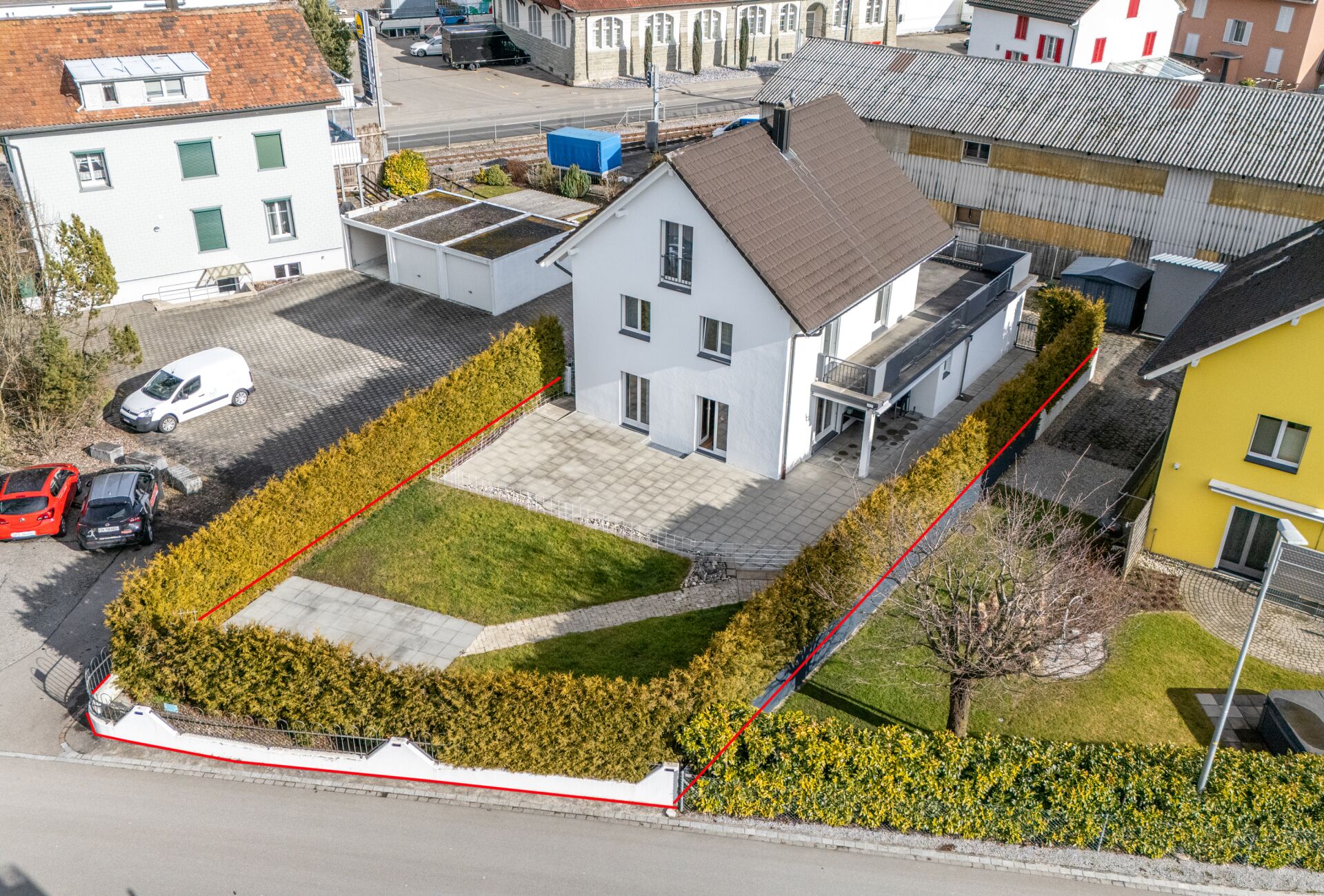 Drohnenaufnahme eines Einfamilienhauses mit Garten und Einfriedung