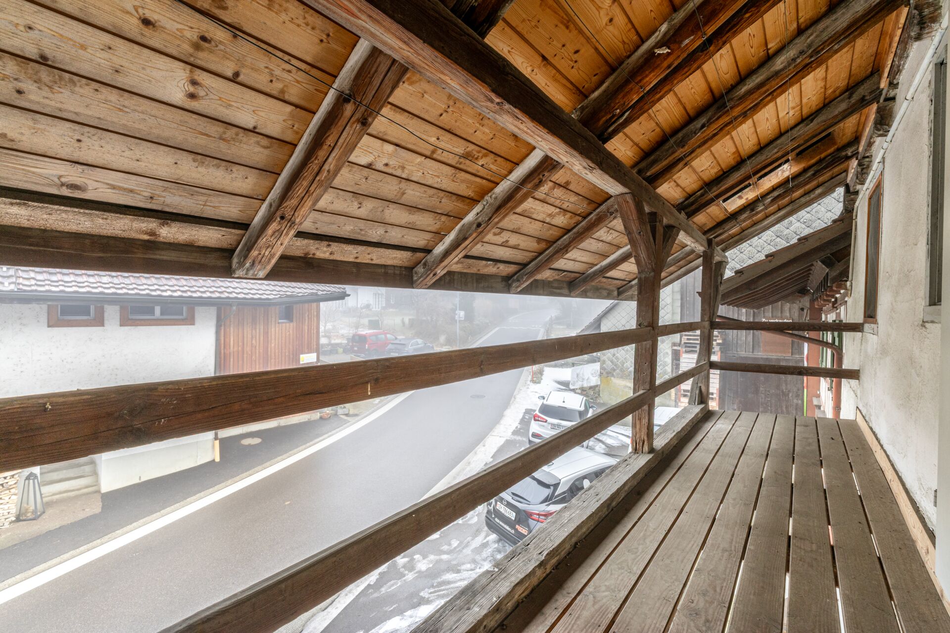 Überdachter Holzbalkon mit Straßenblick