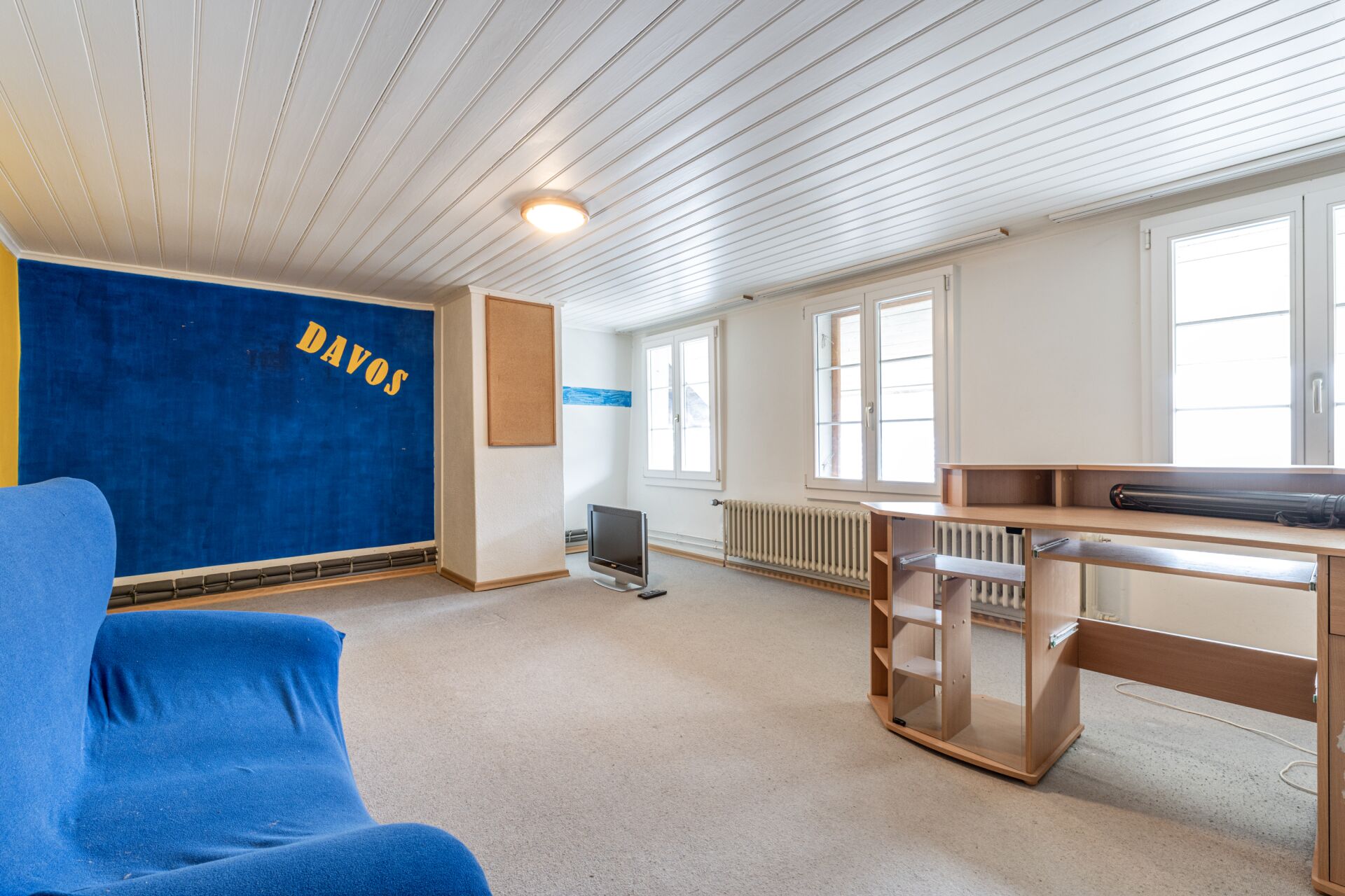 Großer heller Wohnraum mit blauer Wand und Arbeitsbereich