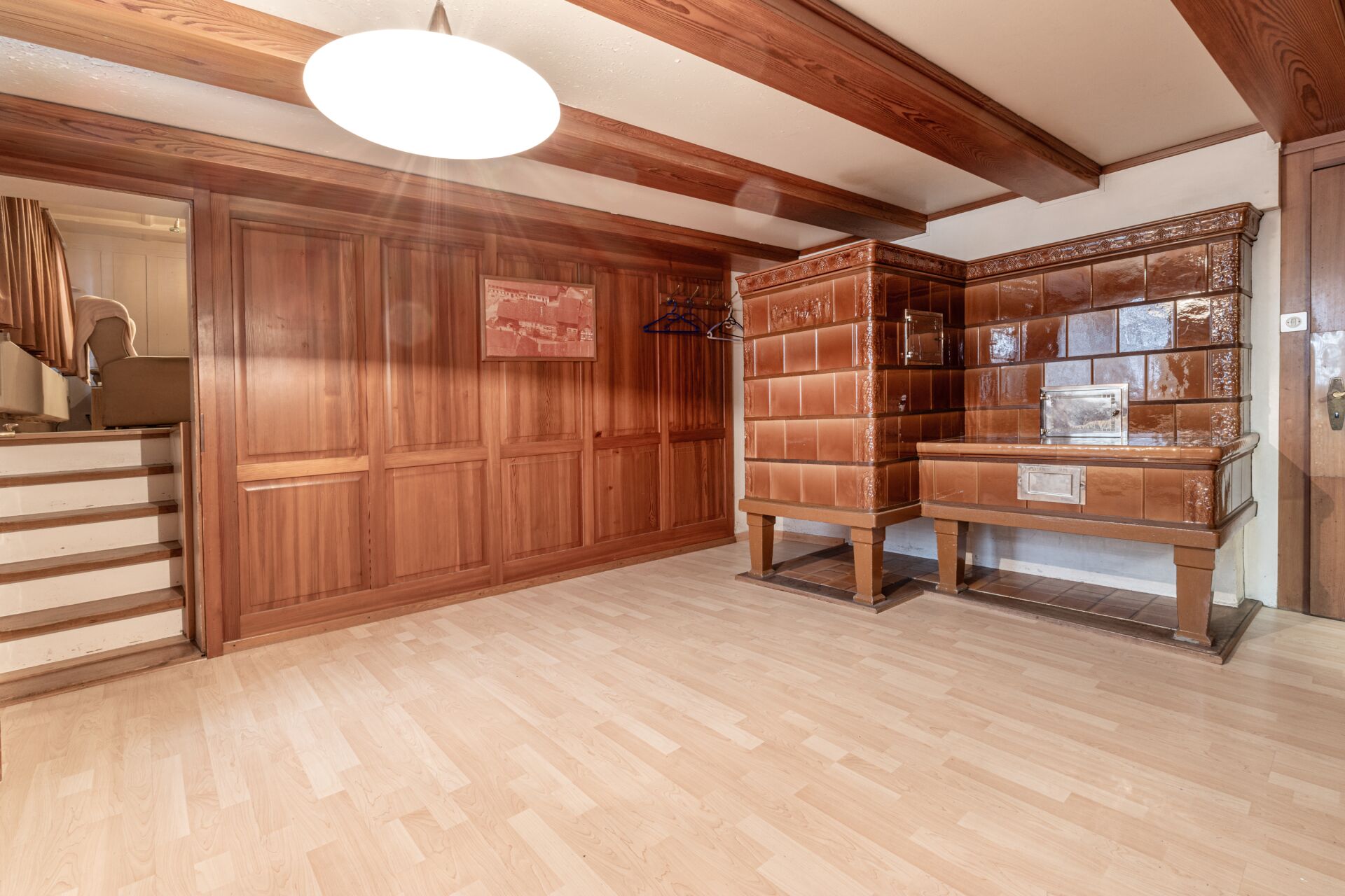 Rustikaler Wohnraum mit Holzvertäfelung und Kachelofen