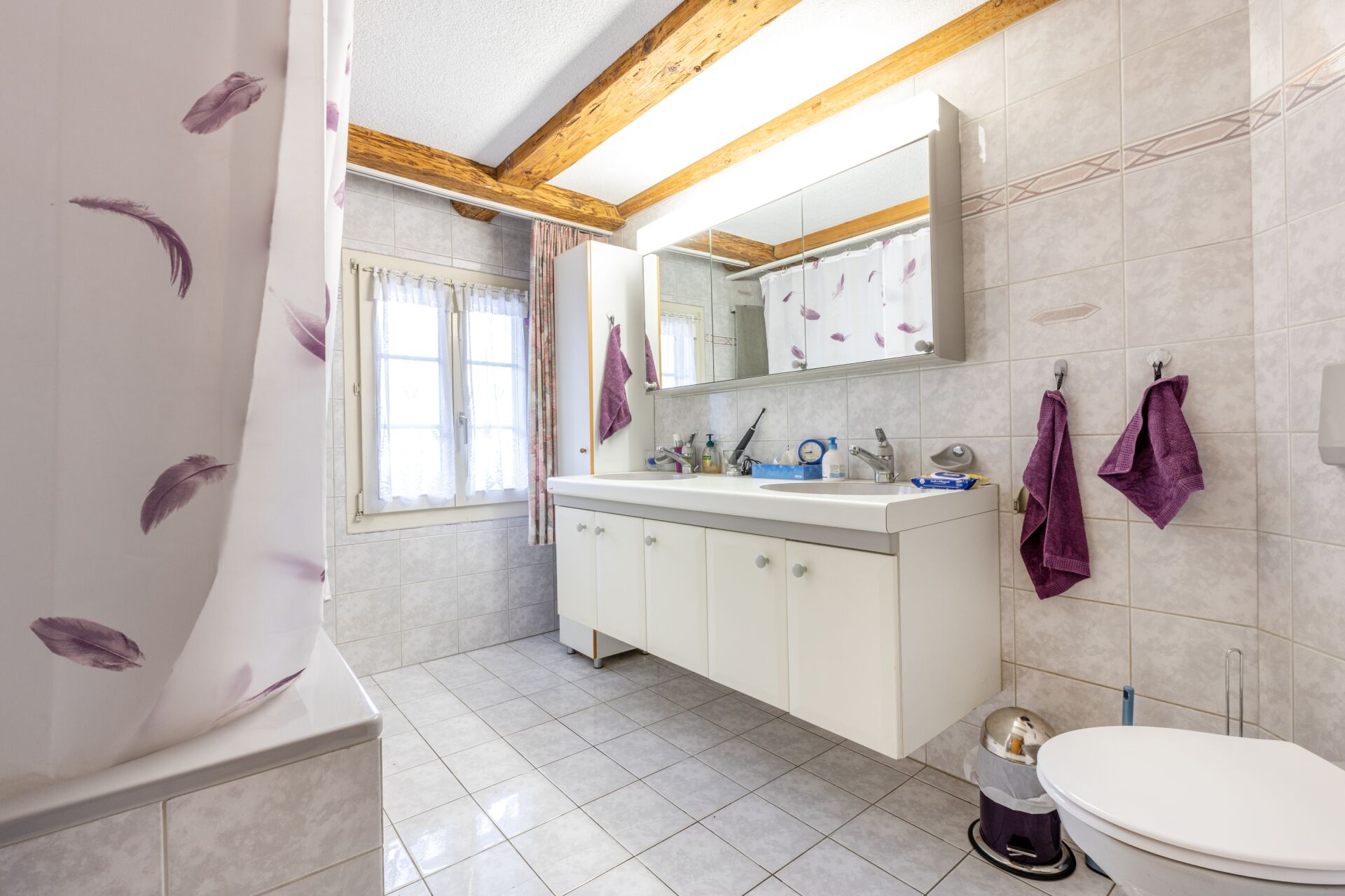 Badezimmer mit Dachbalken und Fliesen