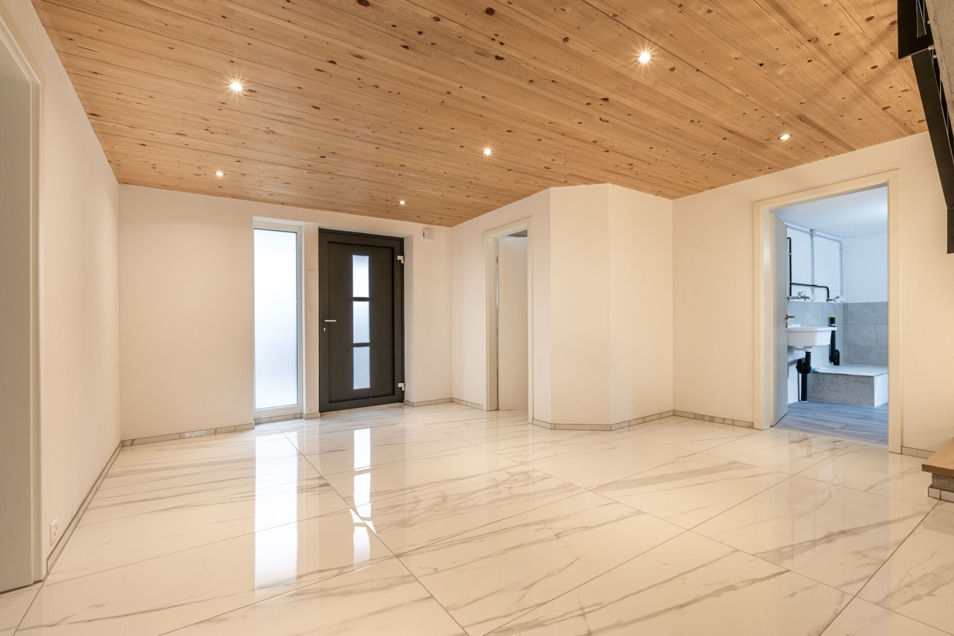 Moderner Eingangsbereich mit Holzdecke und großformatigem Boden