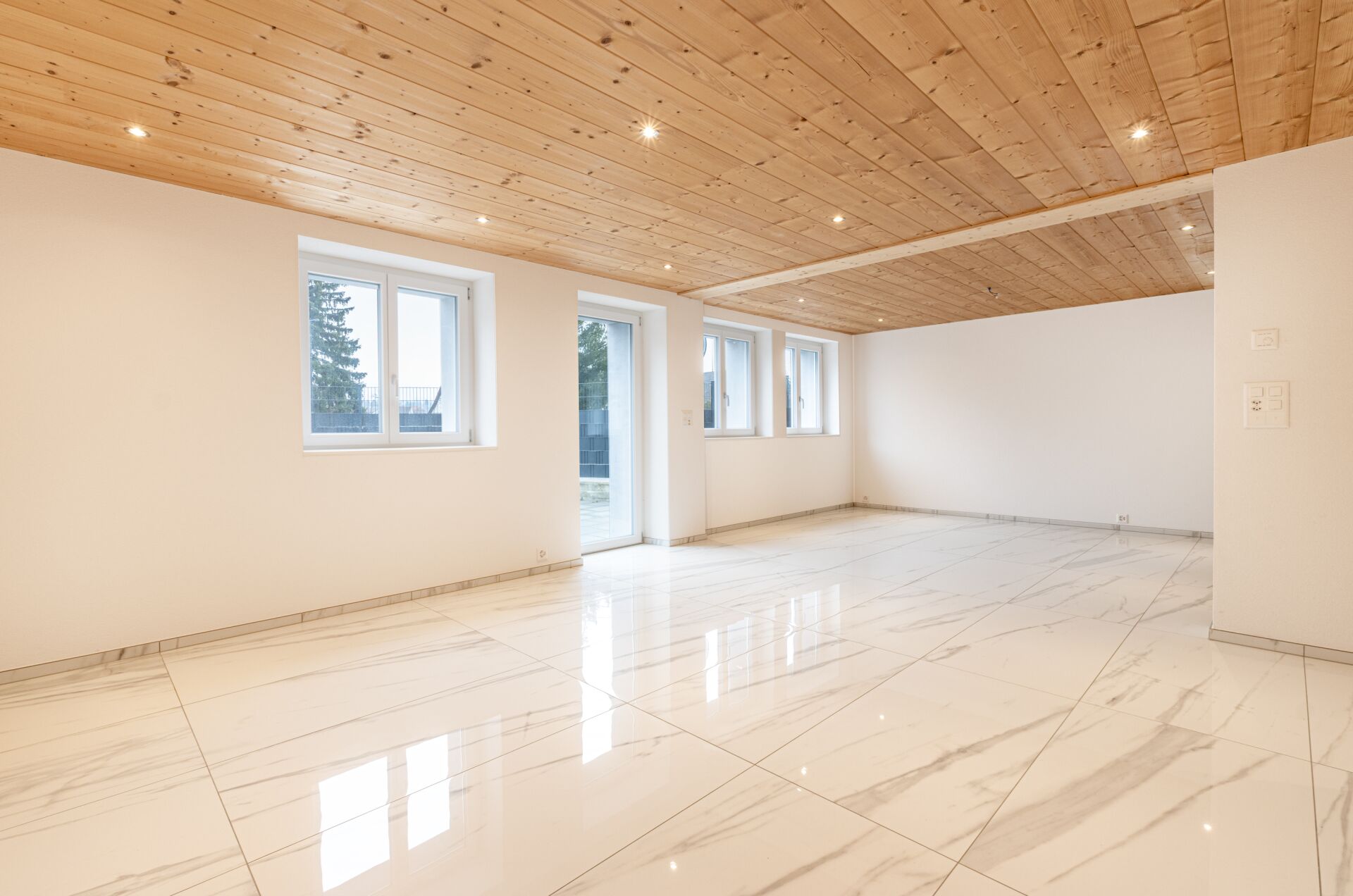 Heller leerer Innenraum mit Holzdecke und großformatigen Fliesen