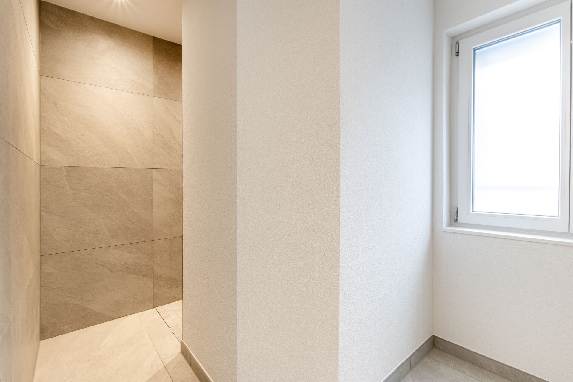 Heller Flur mit Fenster und gefliestem Übergang