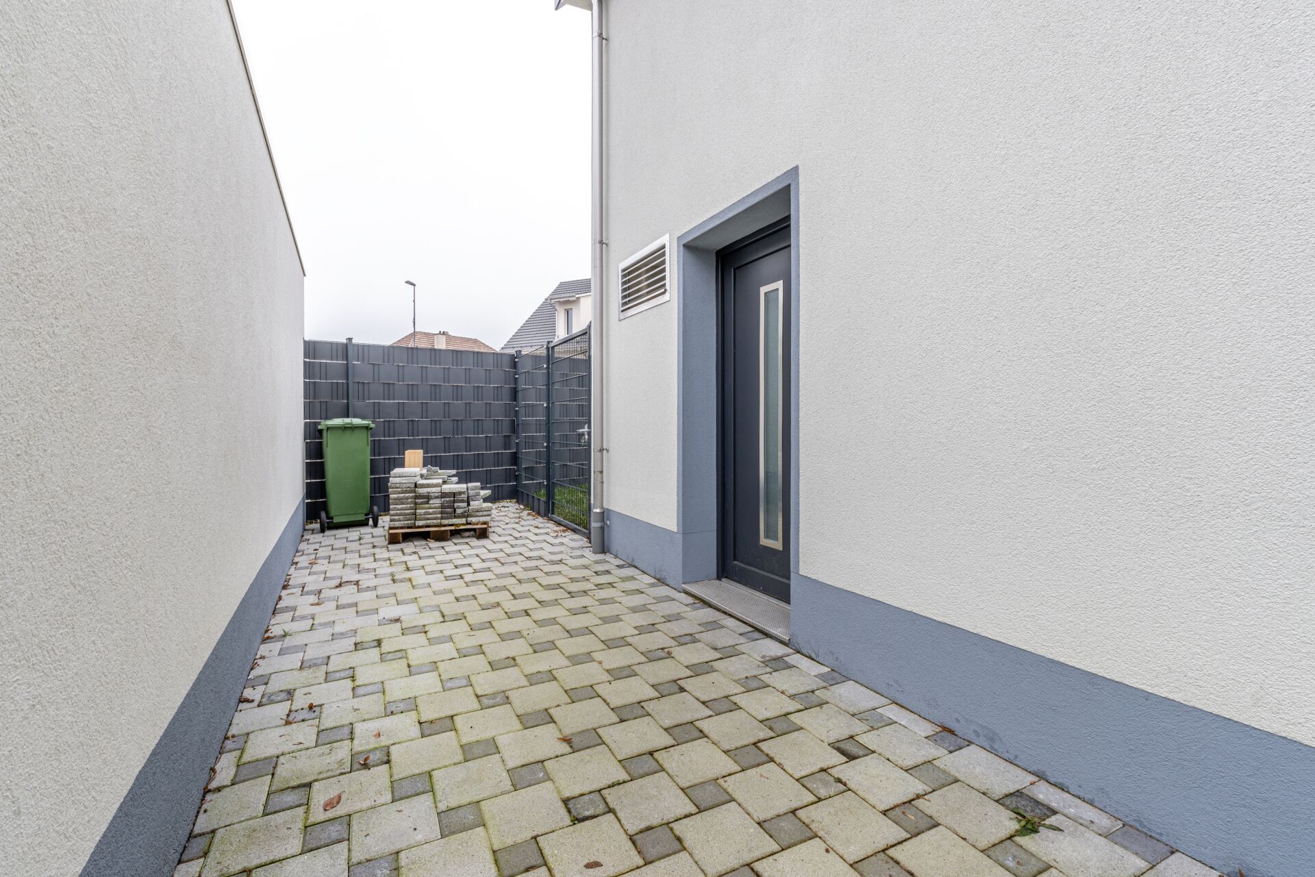 Schmale gepflasterte Hausseite mit Eingang