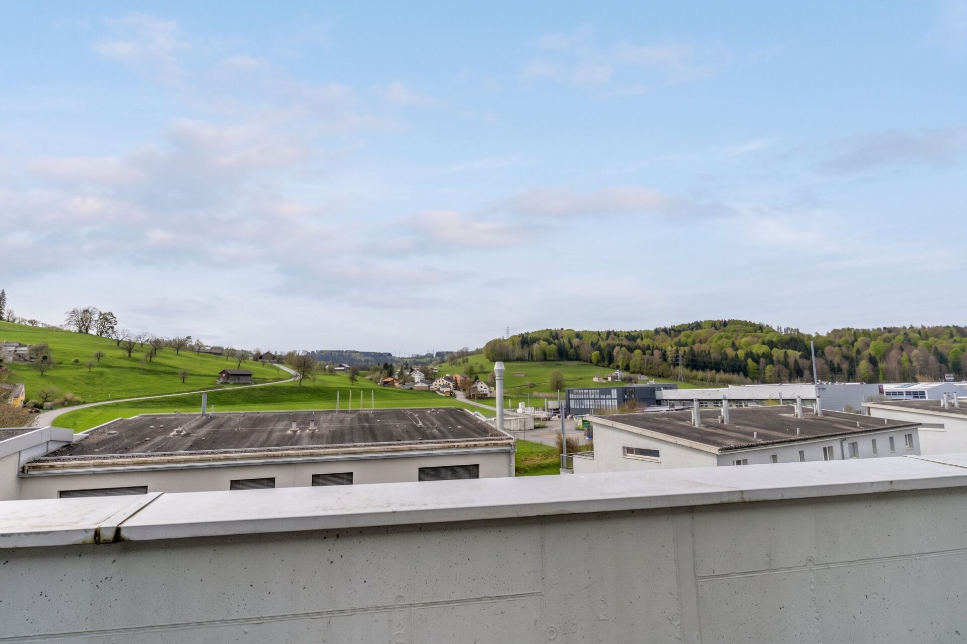 Blick von einer Dachterrasse auf grüne Hügellandschaft