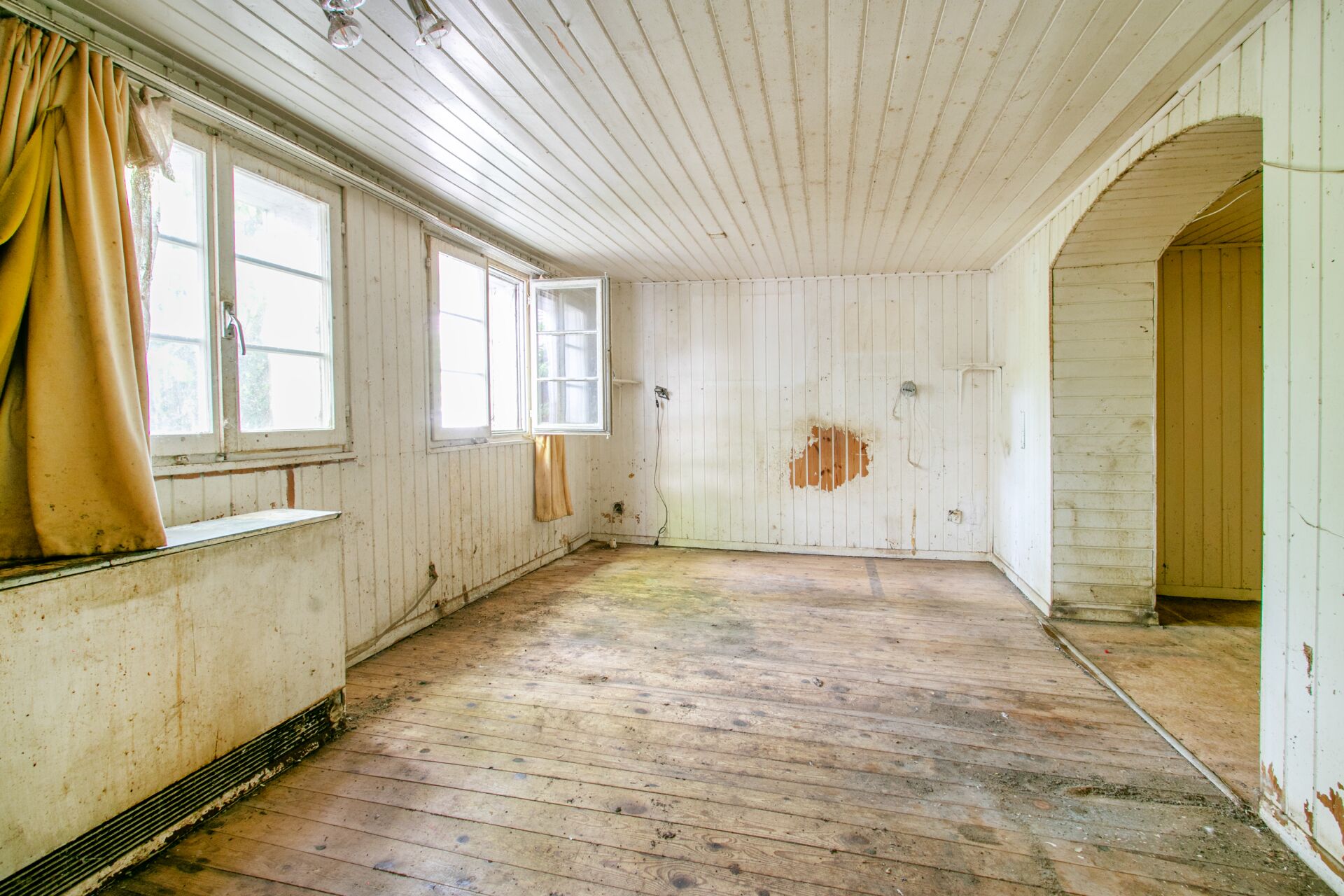 Renovierungsbedürftiger, heller Raum mit Holzverkleidung