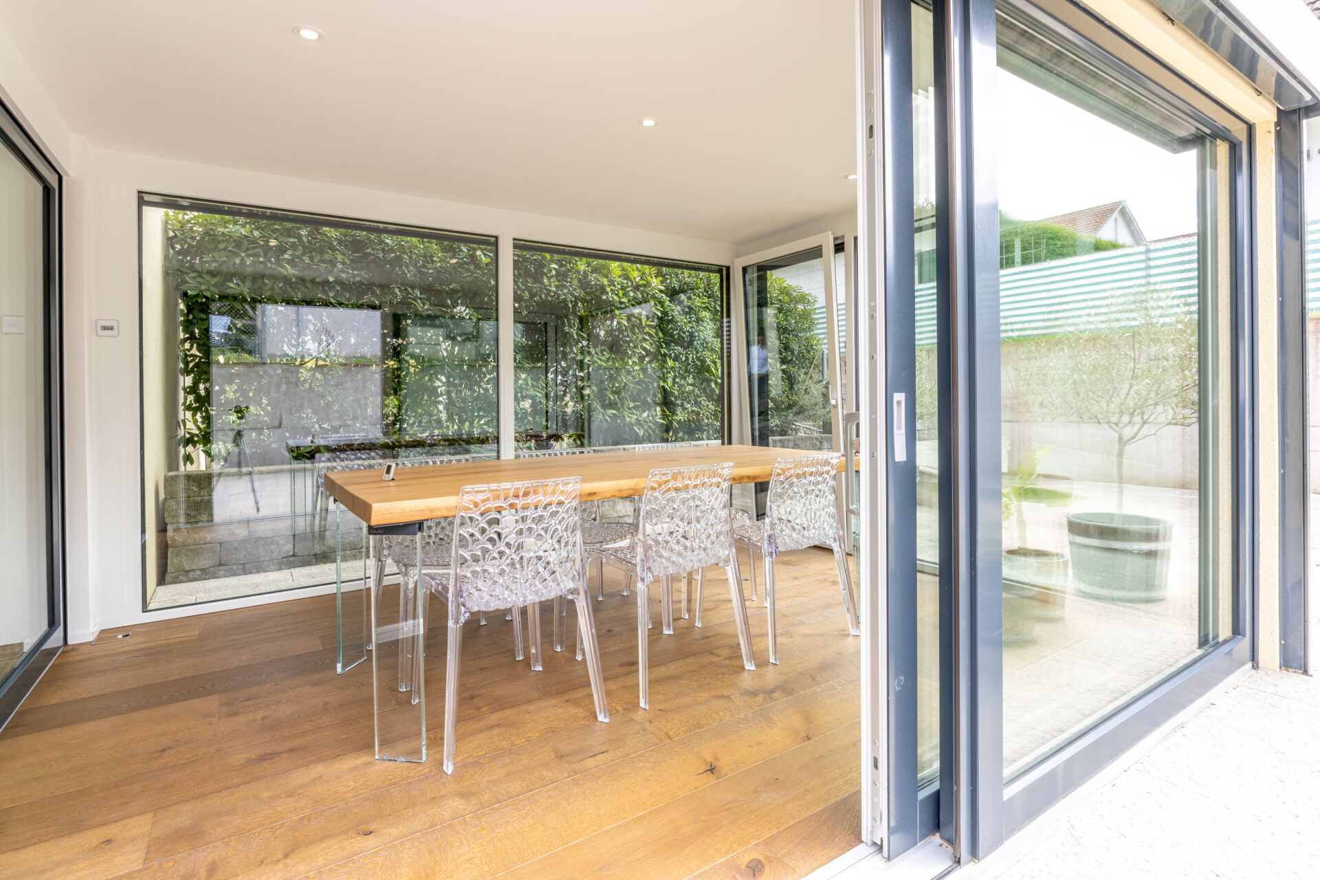 Esszimmer mit großen Glasfronten und Gartenausblick