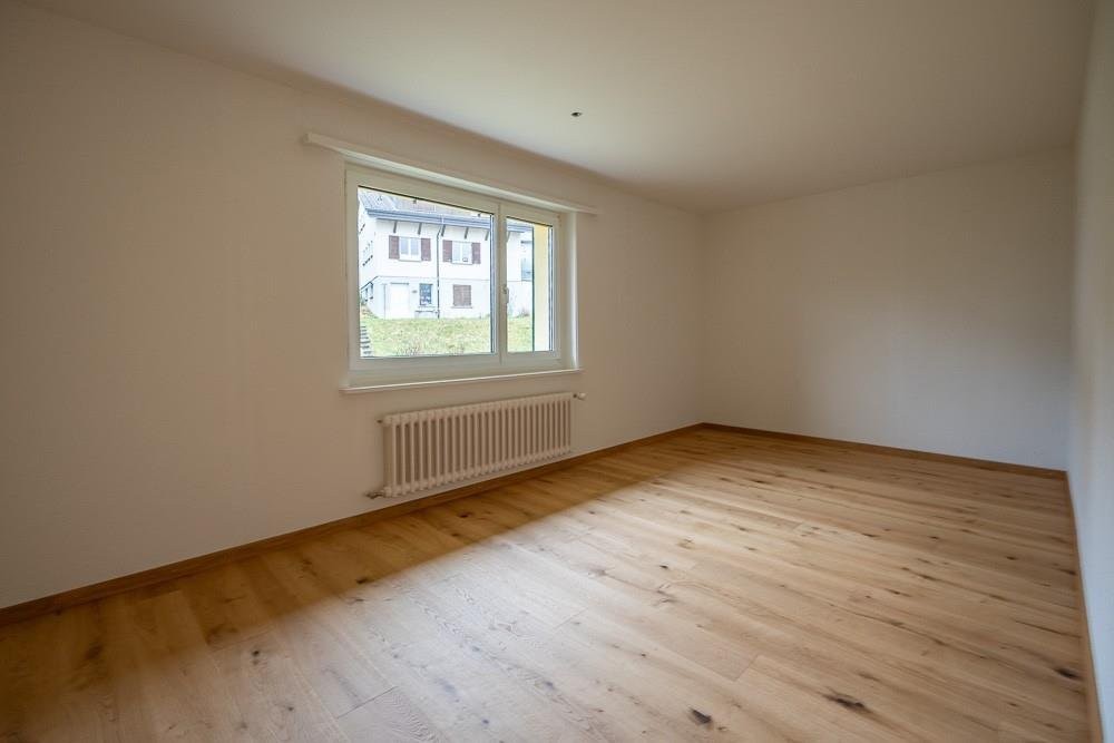Leerer, frisch renovierter Wohnraum mit Fenster und Heizkörper