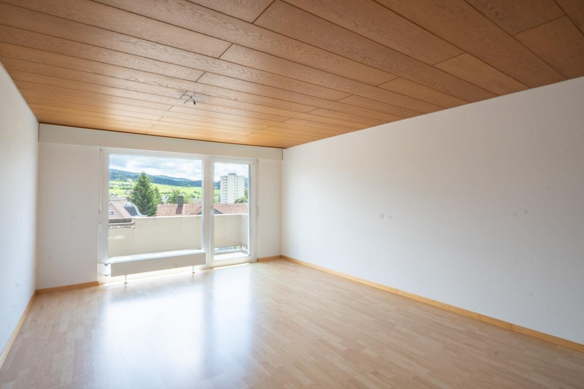 Leerer Wohnraum mit Balkon und Holzdecke