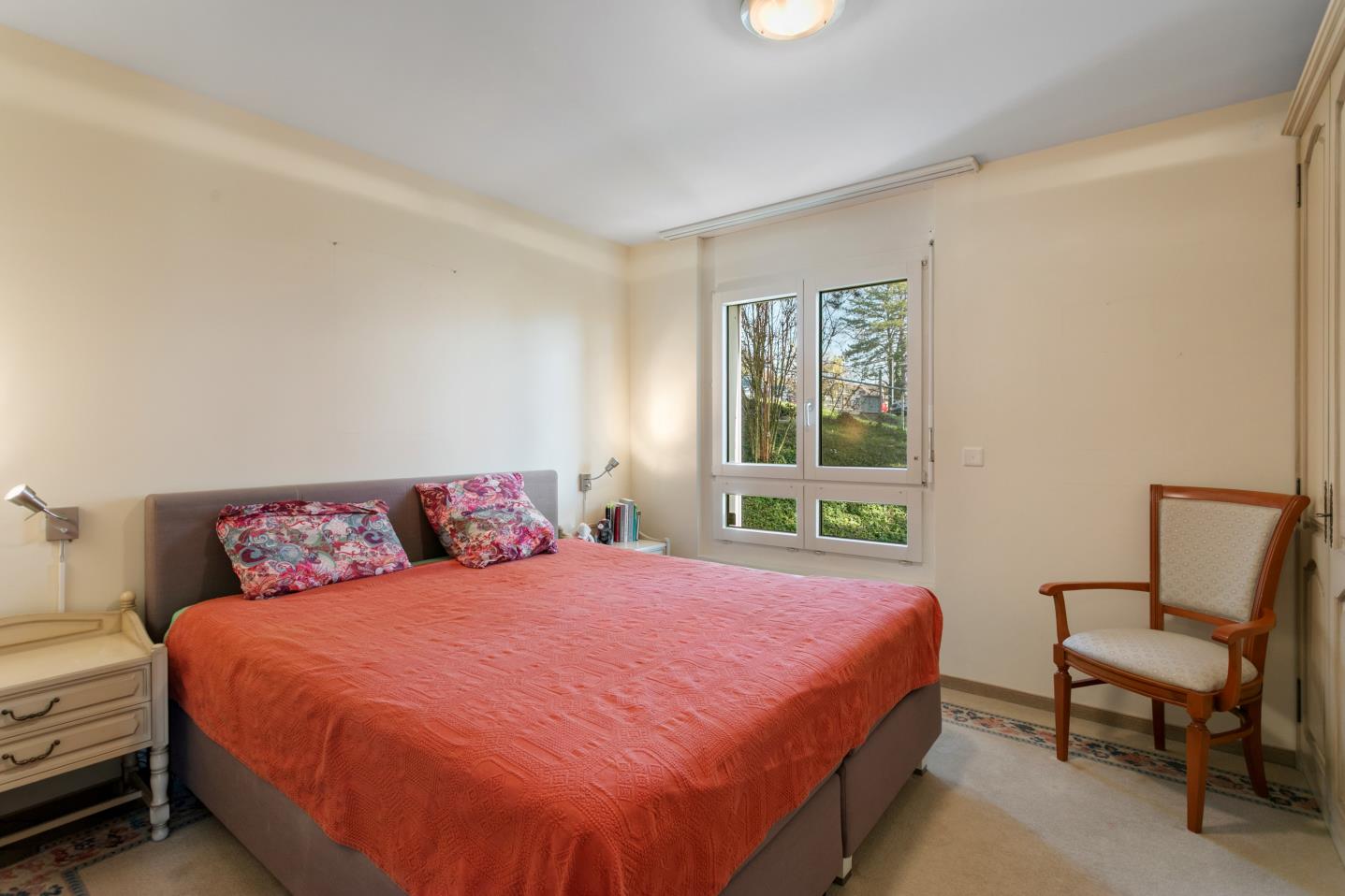 Helles Schlafzimmer mit Doppelbett und Fensterblick ins Grüne