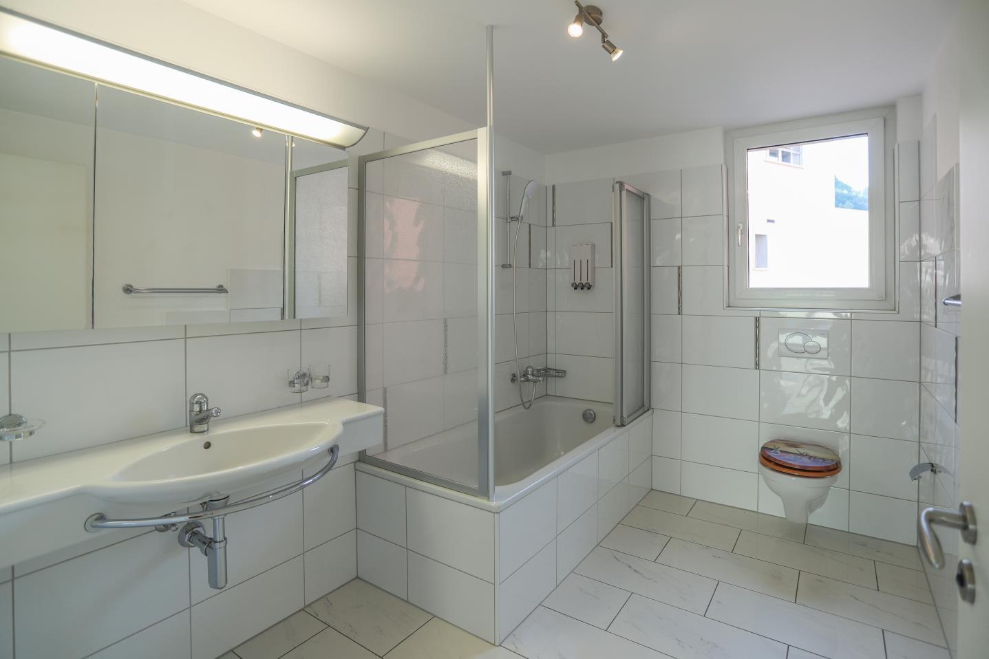 Helles Badezimmer mit Badewanne und Fenster