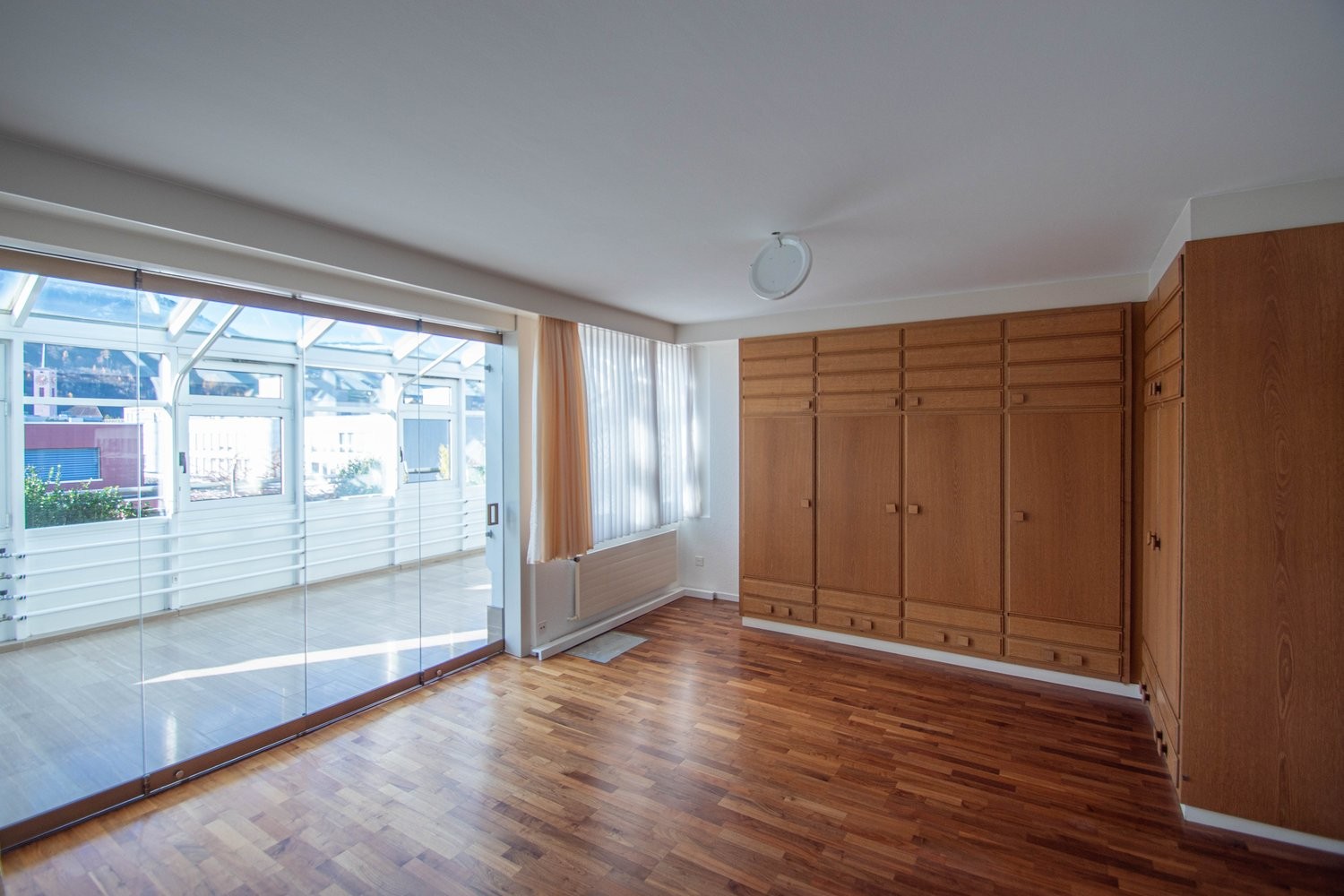 Helles Zimmer mit Holzschränken und Wintergarten