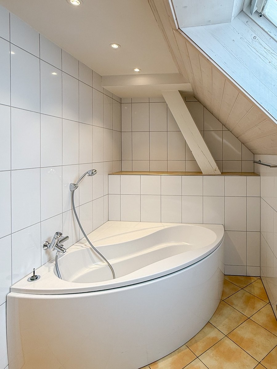 Badezimmer mit Eckwanne unter Dachschräge