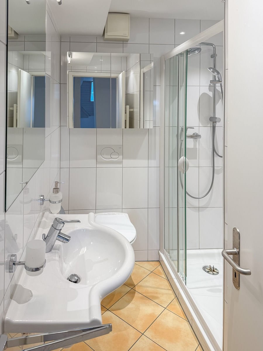 Kleines helles Badezimmer mit Dusche und Waschtisch