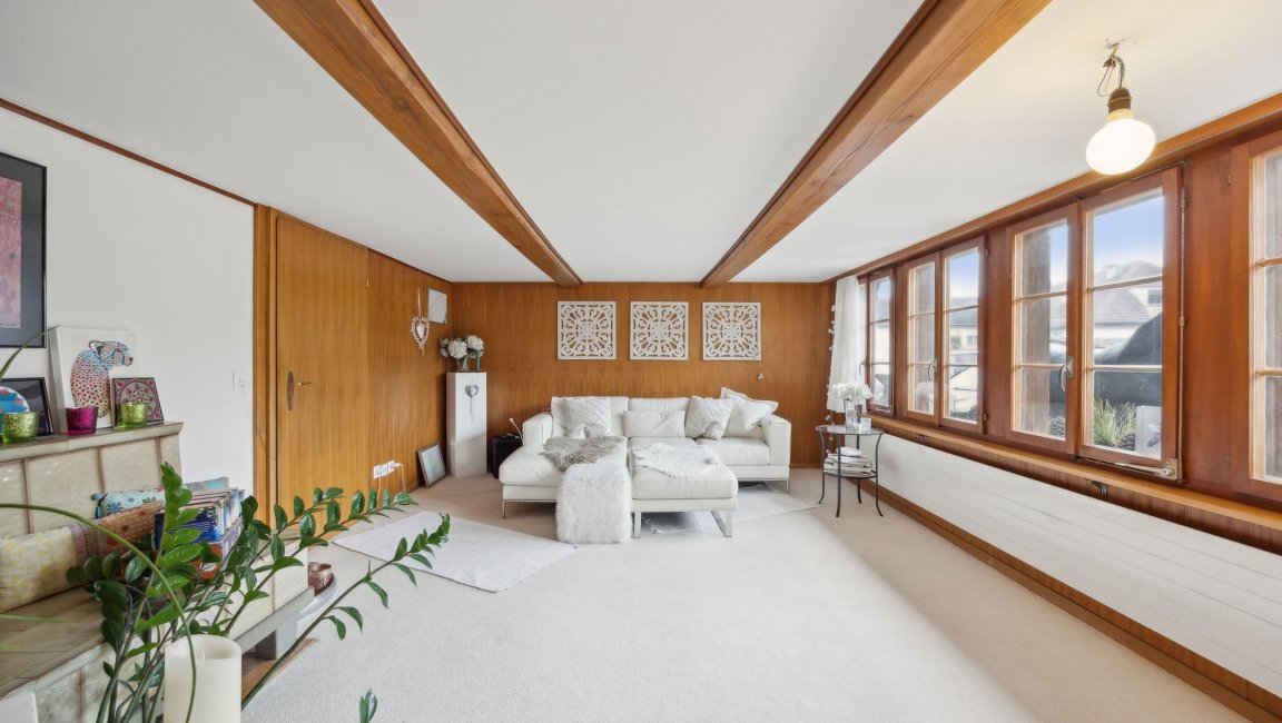 Helles Wohnzimmer mit Holzverkleidung und großen Fenstern