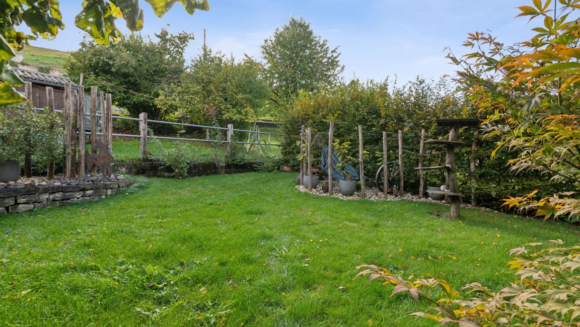 Garten mit grüner Rasenfläche und Naturholz-Elementen