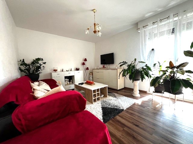 Helles Wohnzimmer mit rotem Sofa und vielen Pflanzen