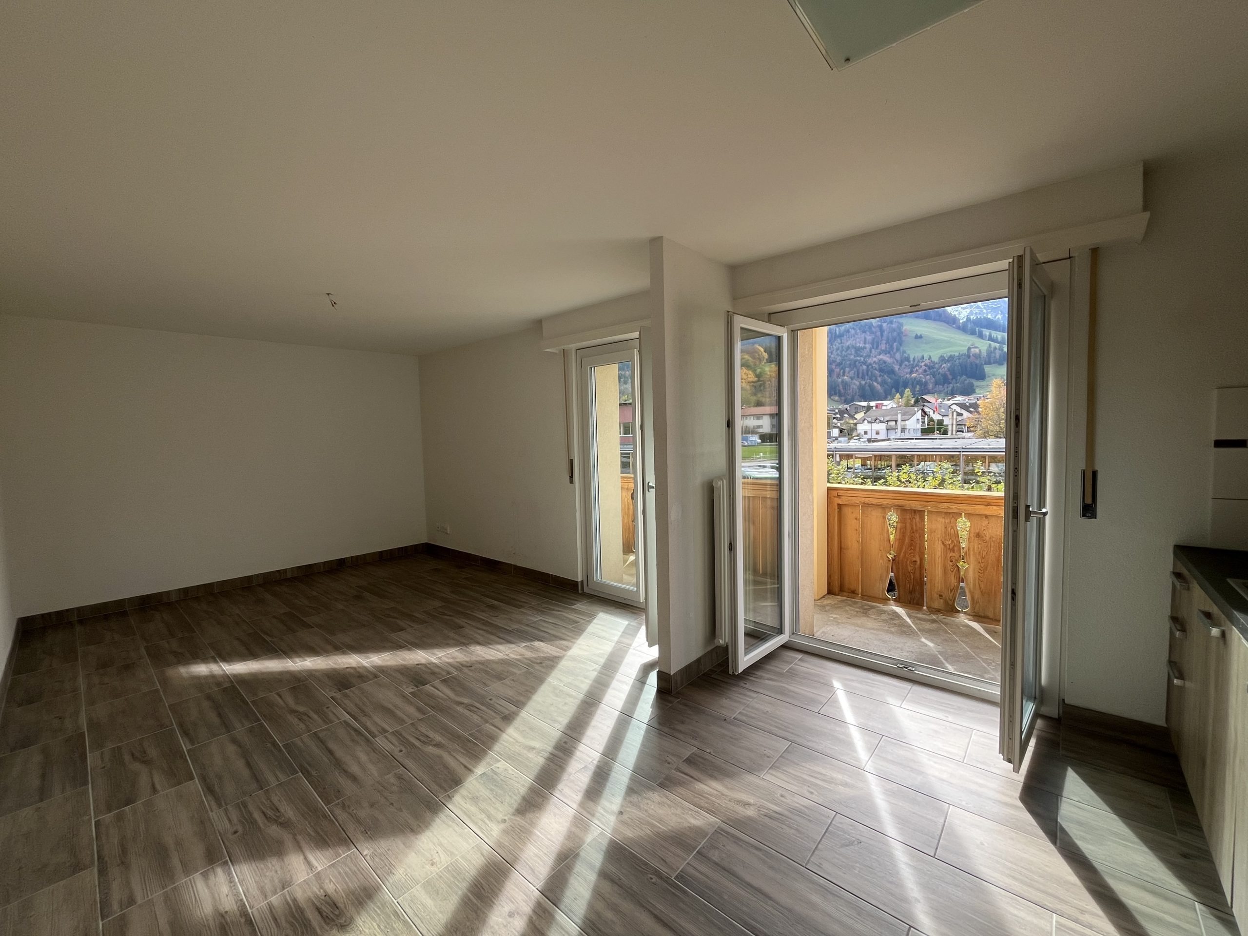 Leerer Wohnraum mit Balkon und Bergblick