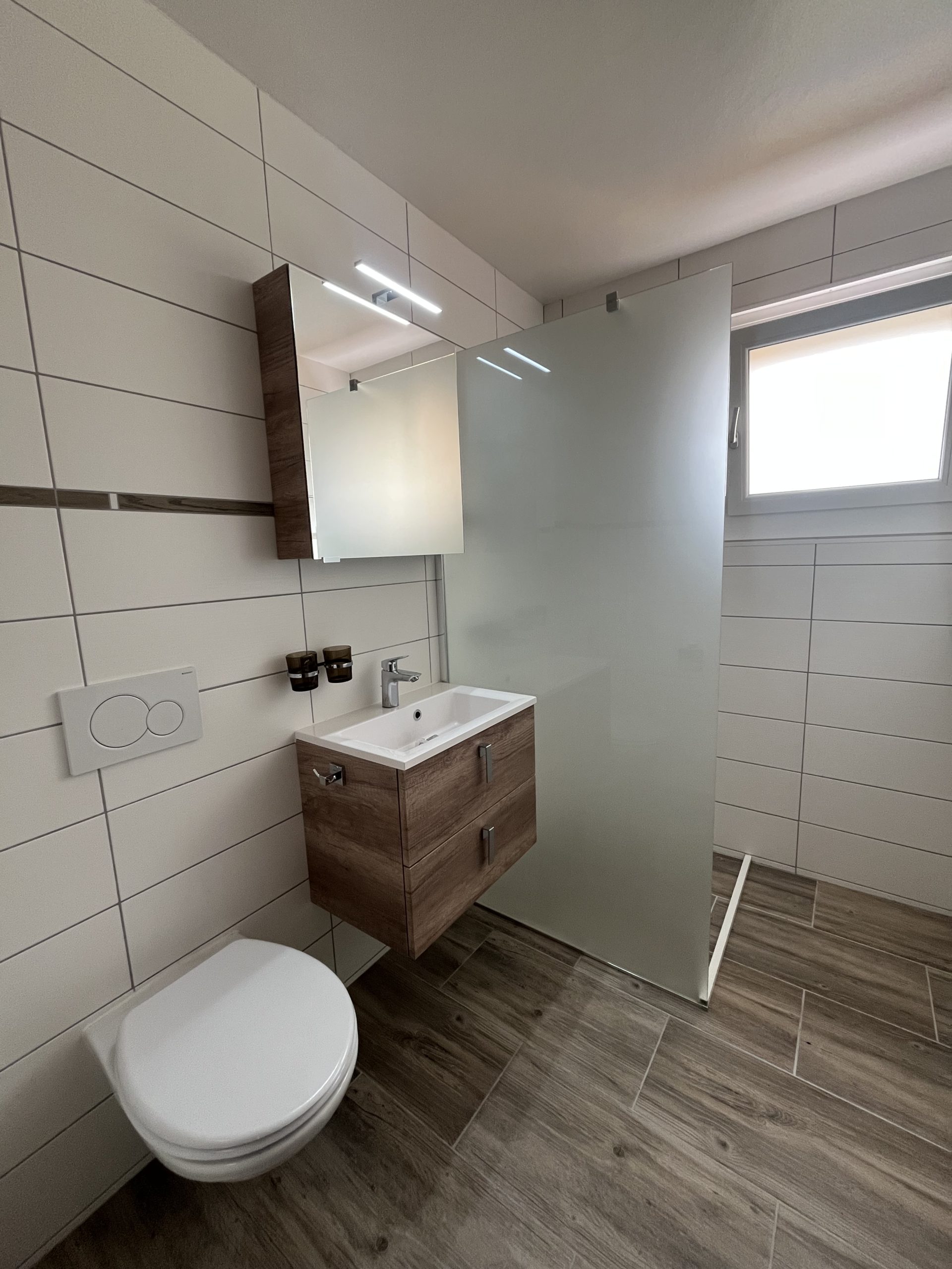 Modernes Gäste-WC mit Holzwaschtisch und Glasabtrennung