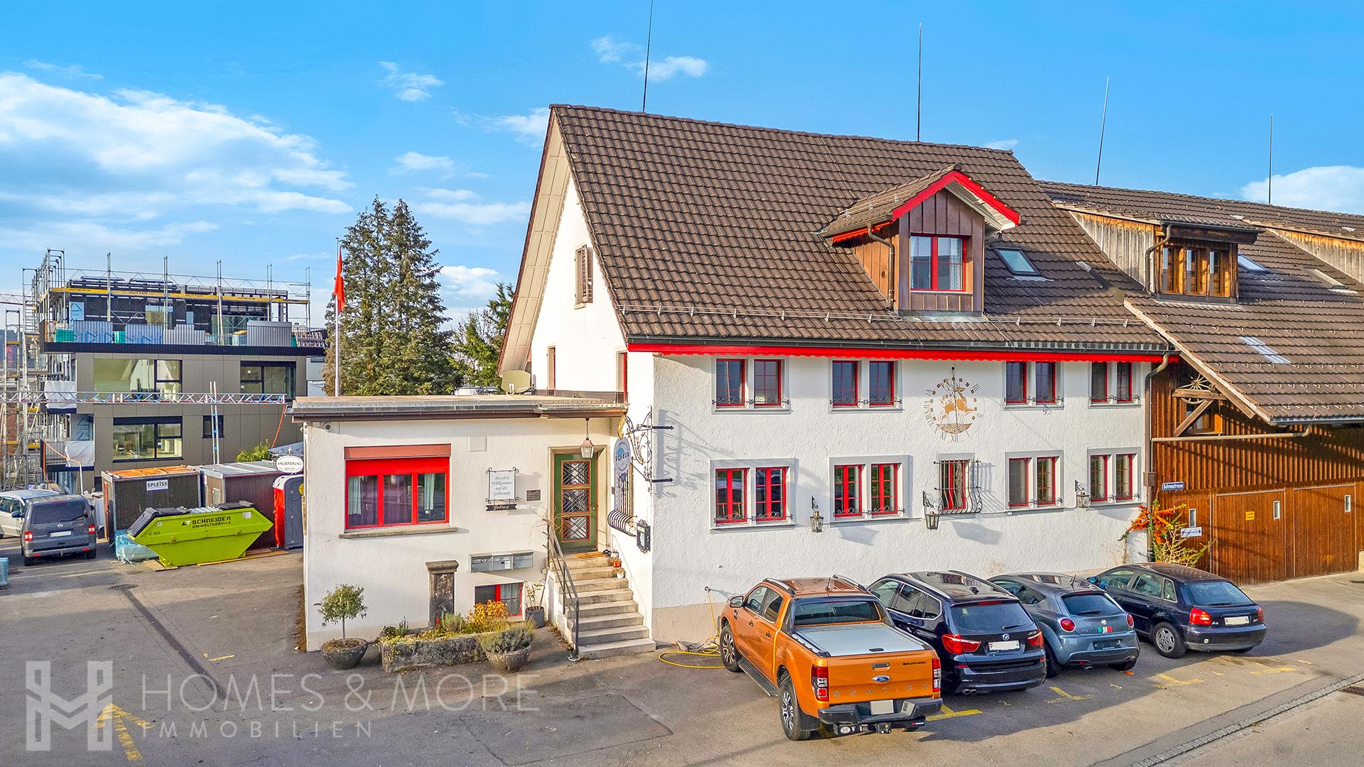 Außenansicht eines Hauses mit Nebengebäude und Parkplätzen
