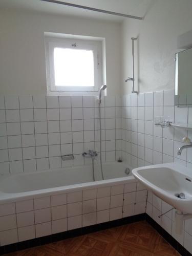 Helles Badezimmer mit Badewanne und Fenster