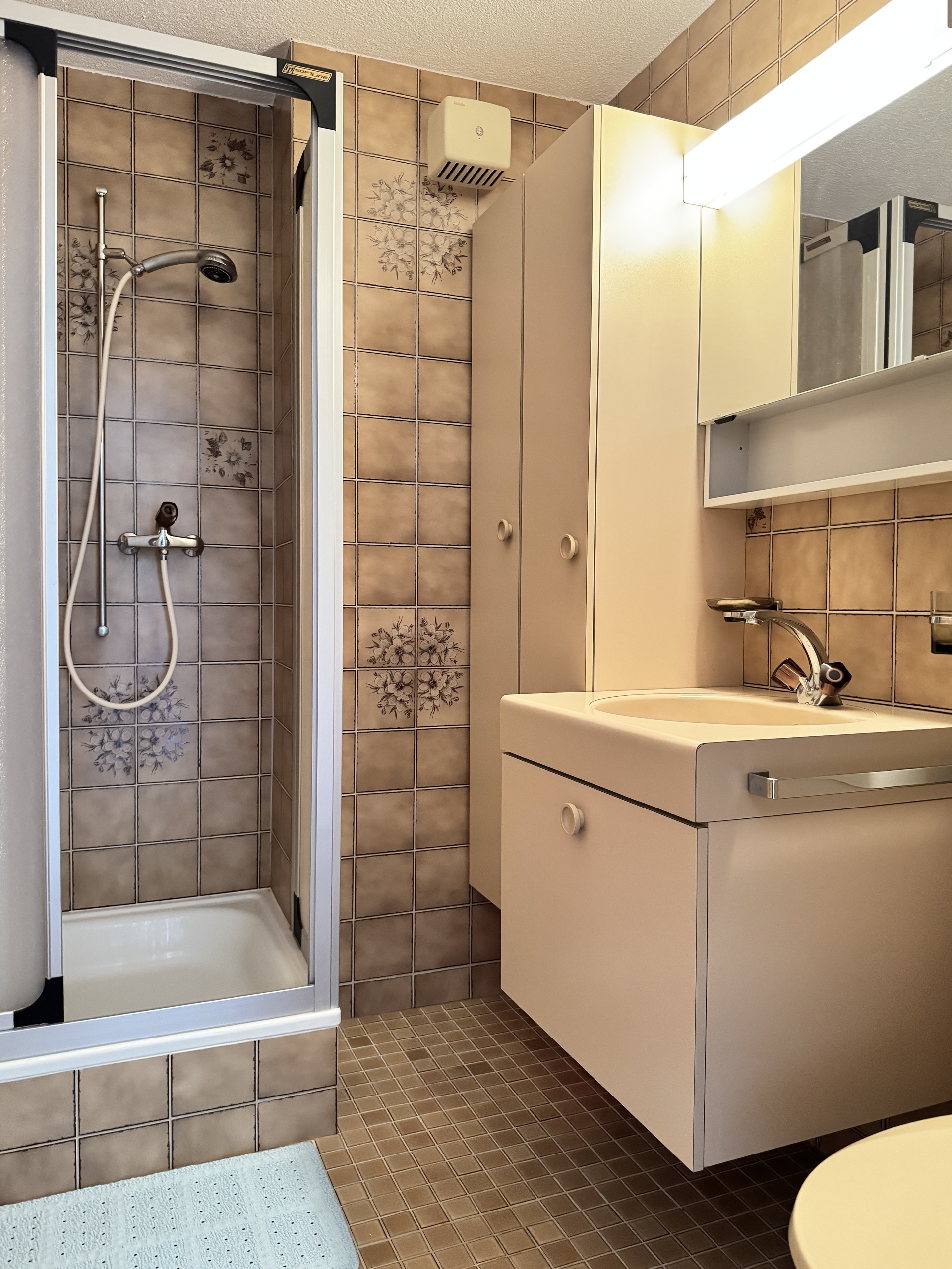 Kleines Badezimmer mit Duschkabine und Waschplatz