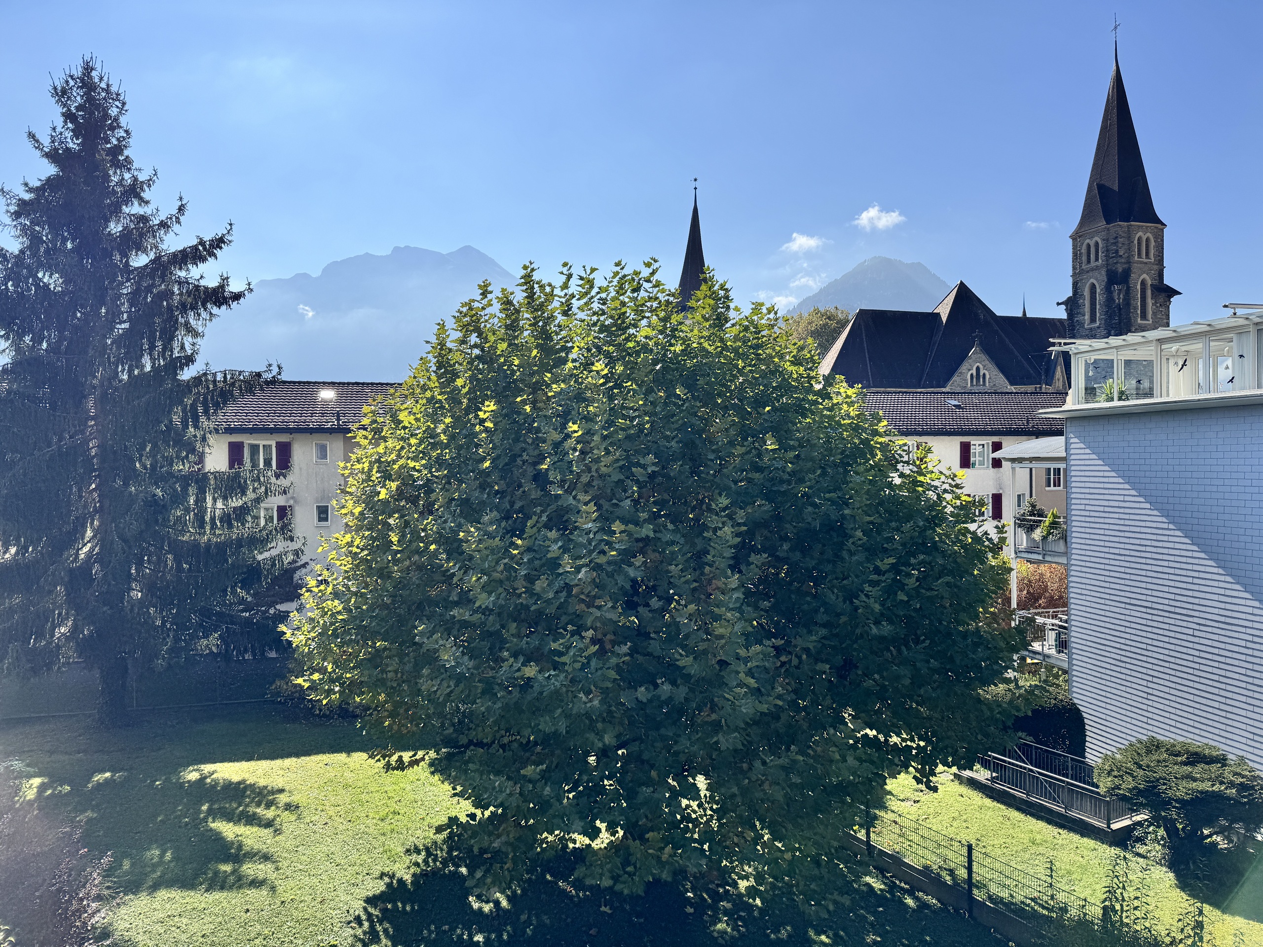 Blick auf Wohnbebauung und Kirchturm mit Bergkulisse