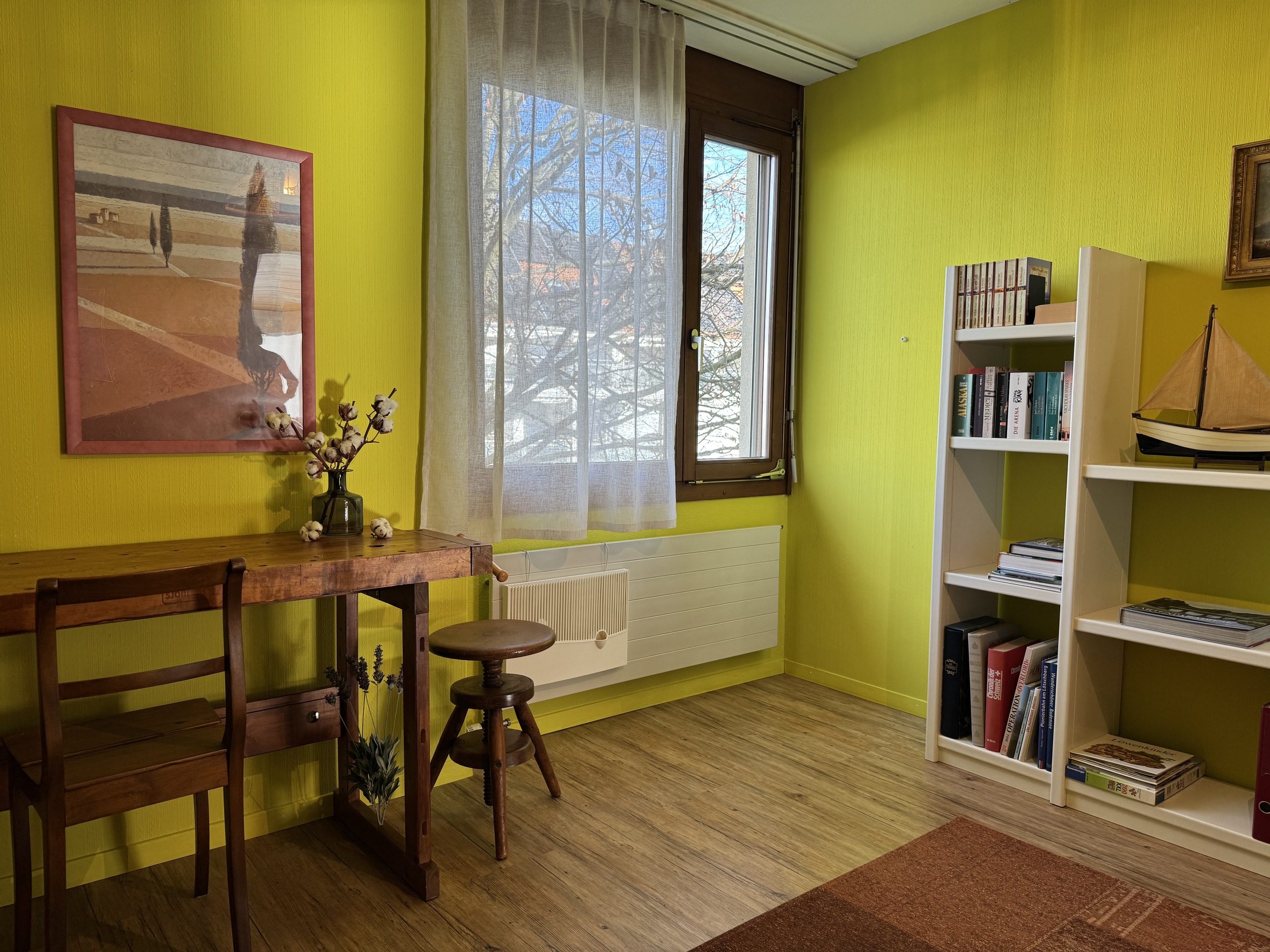 Helles Zimmer mit Schreibtisch und Bücherregal