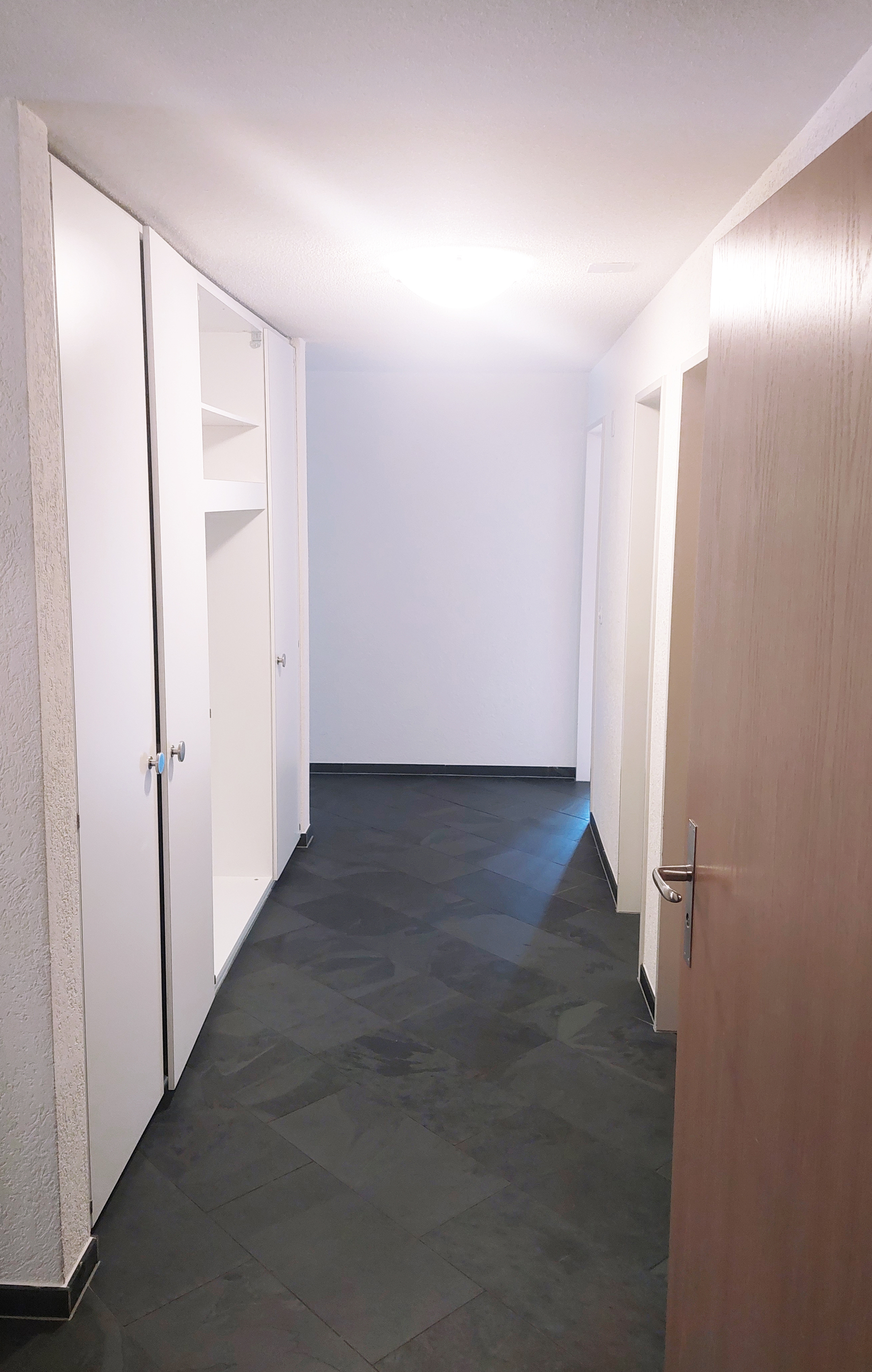 Flur mit dunklem Boden und Einbauschränken