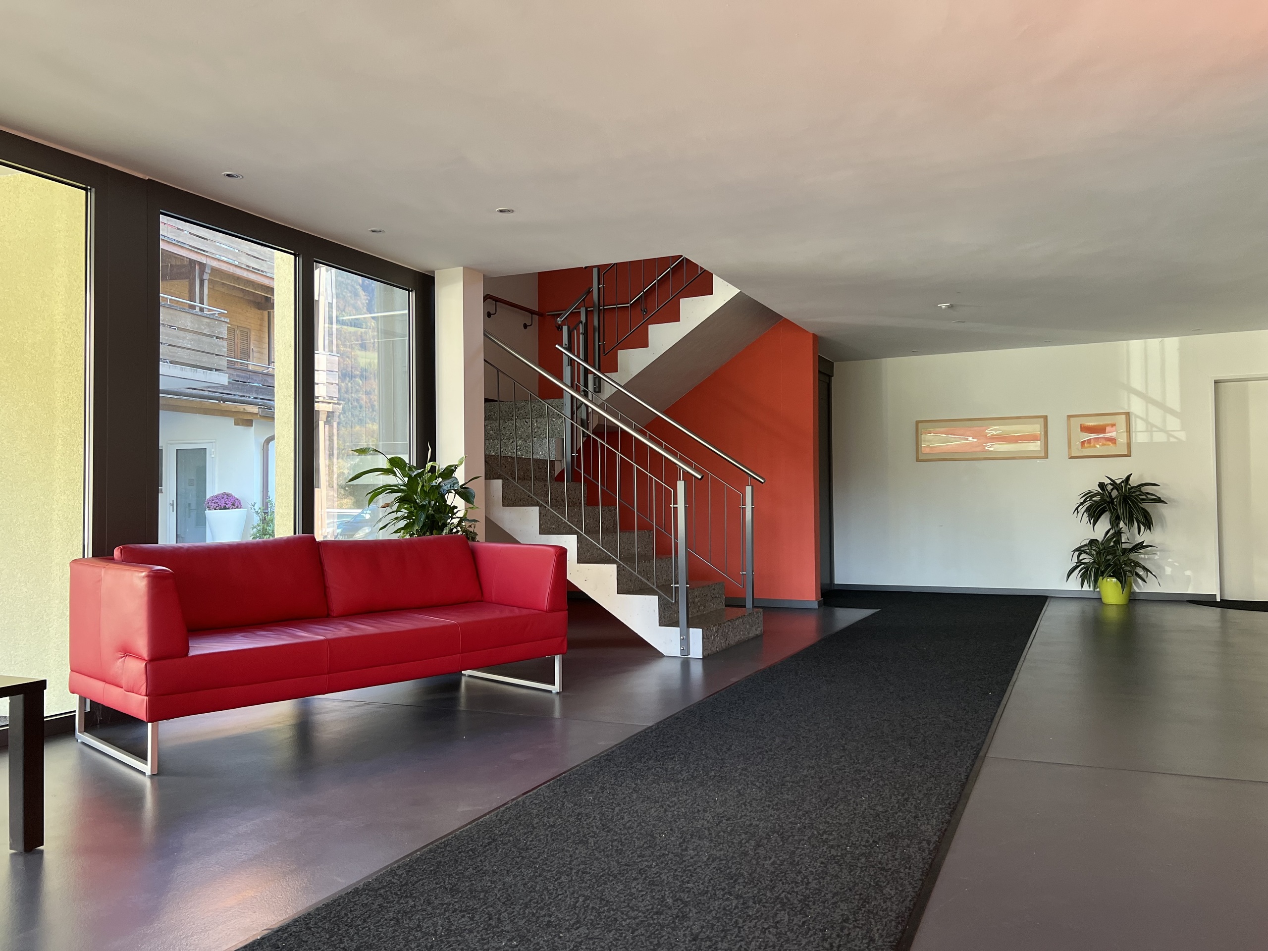 Moderner Eingangsbereich mit Treppe und rotem Sofa