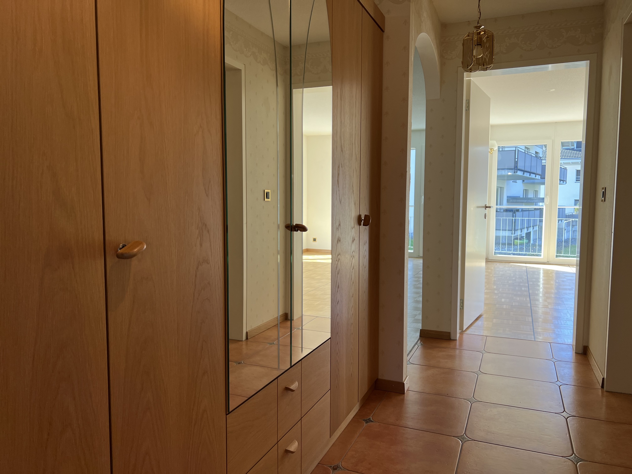 Heller Flur mit Holzschrank und Blick ins Wohnzimmer