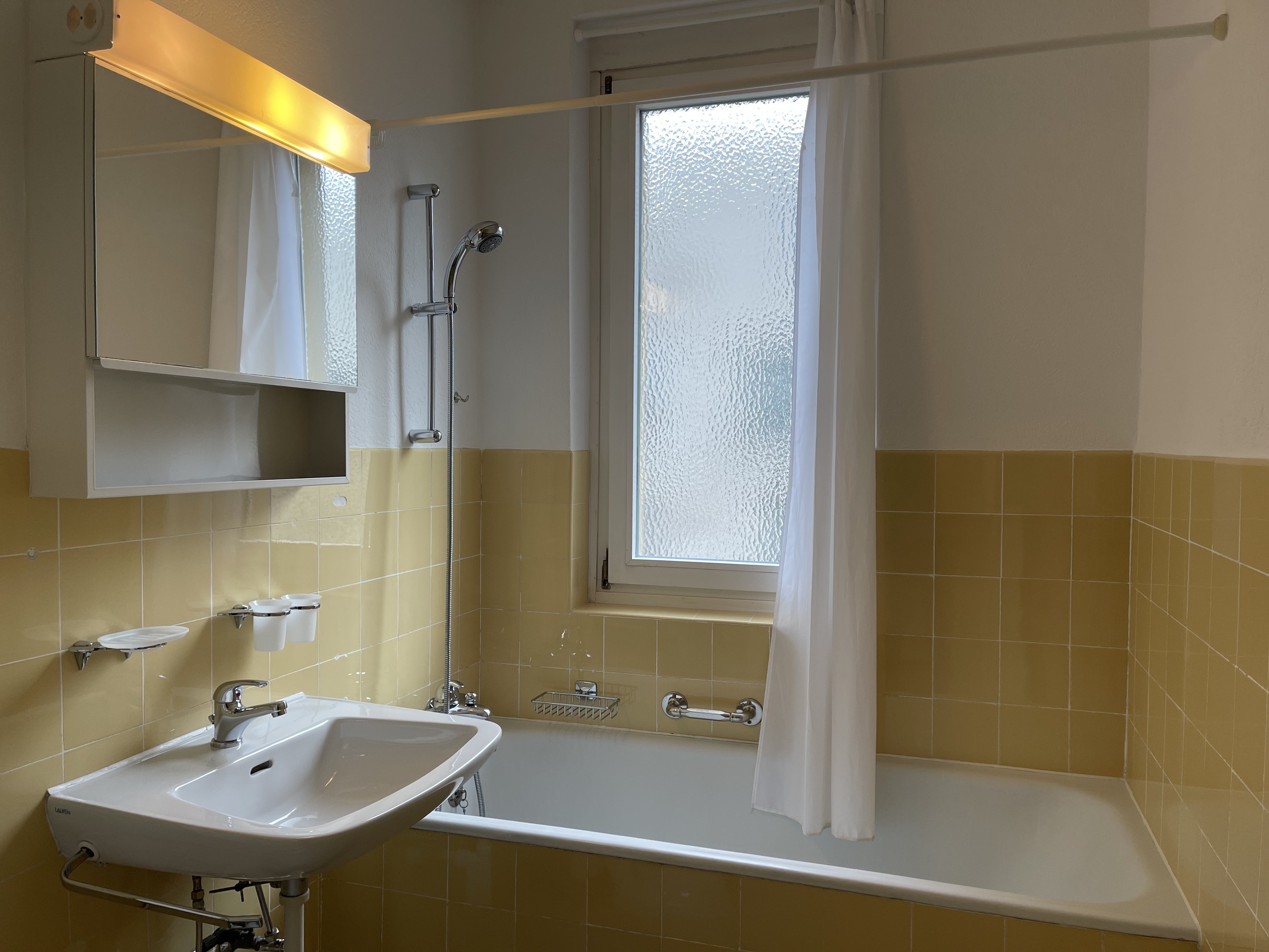 Badezimmer mit gelben Fliesen und Badewanne