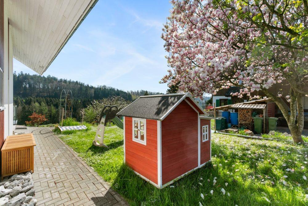 Garten mit Spielhaus und Blumenbaum