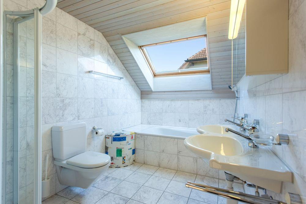 Dachgeschoss-Badezimmer mit Badewanne und Dachfenster
