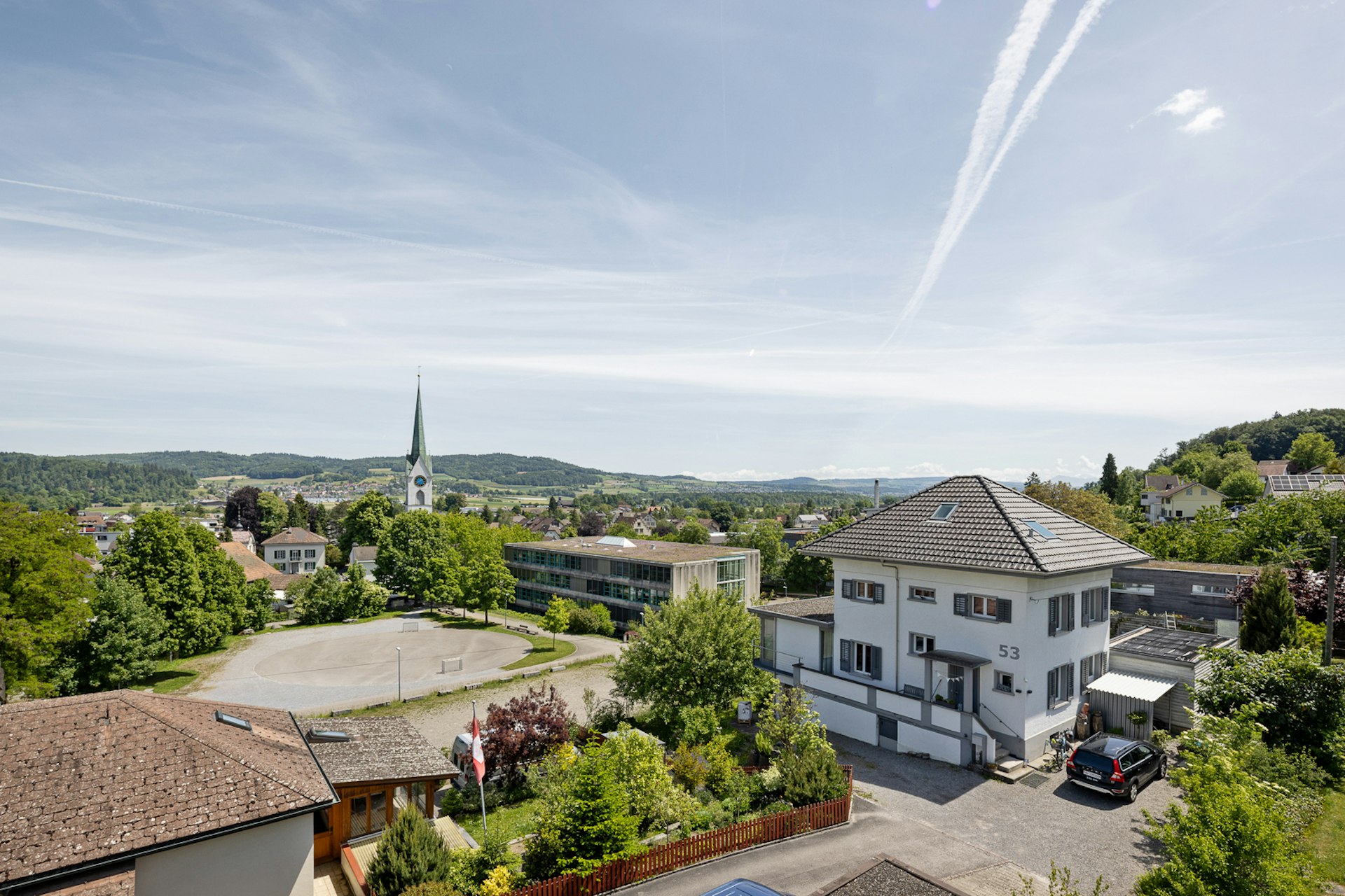 Weitblick über eine grüne Wohnlage mit Kirche und Häusern